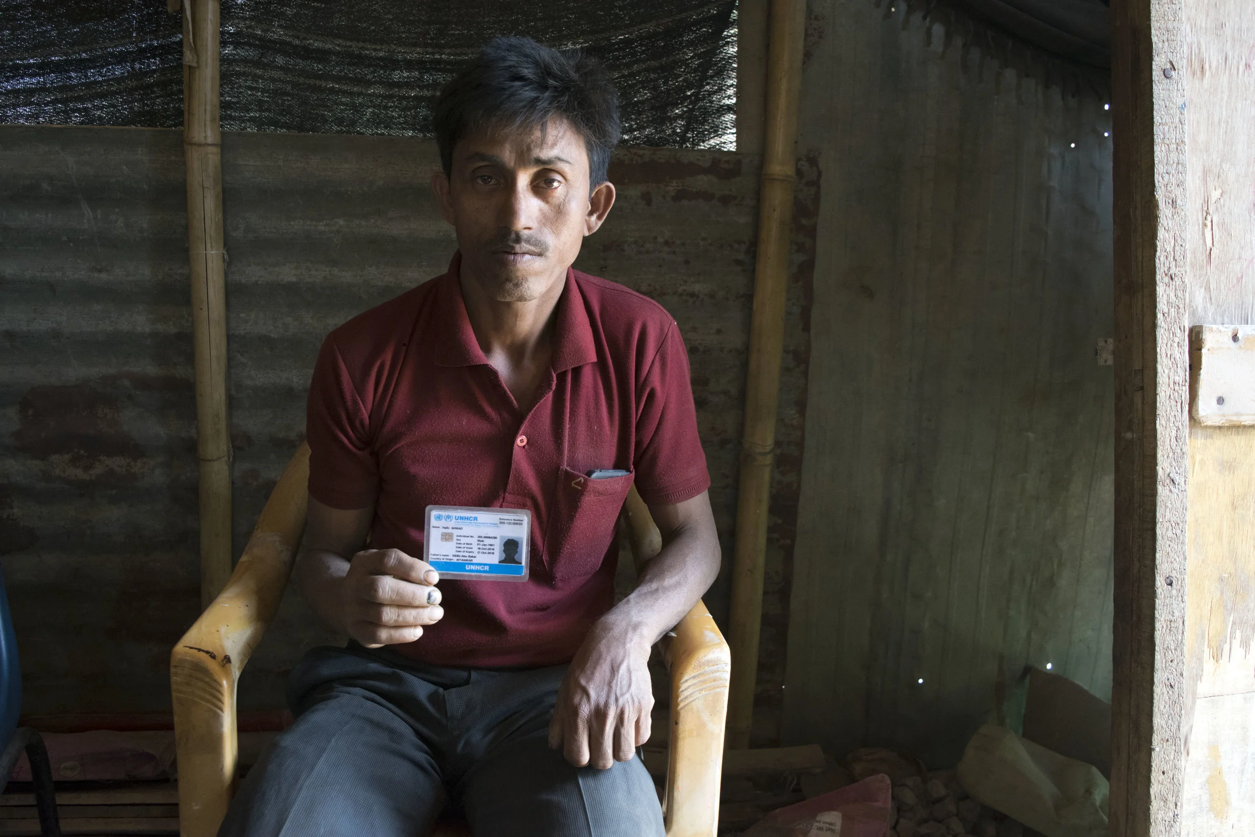A Rohingya refugee holds up his UN-issued identity card, his only identity document as a stateless person. Photo by Meagan Clark.