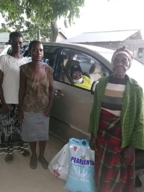 Kwedyo delivers groceries to Sheila Mutoma, in the middle.