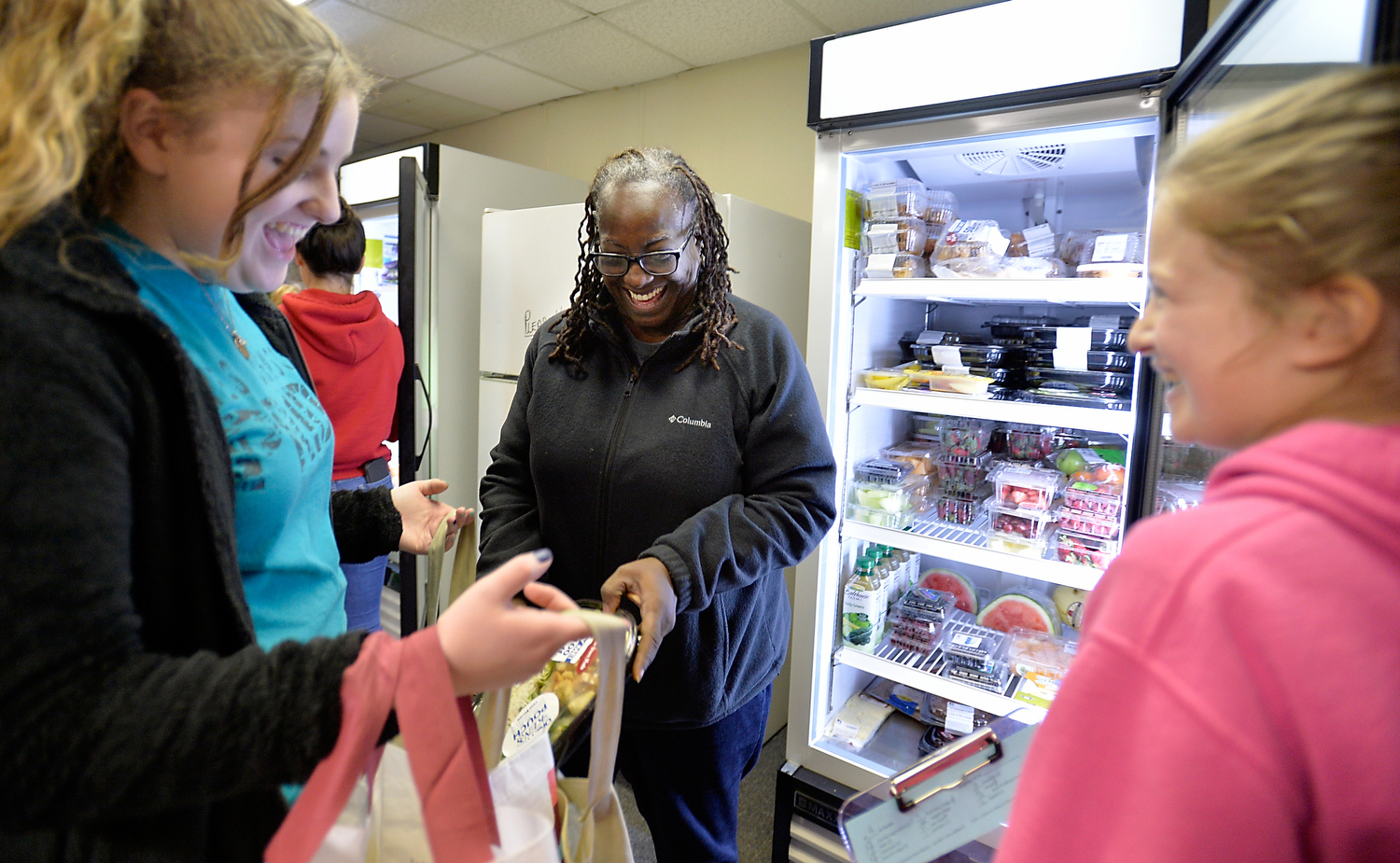 Rosa Lee Robinson, 54, finds a fresh salad she likes from the West Johnston Food Pantry as student volunteers Abigail Jones and Kristen Suggs (right) assist on Wednesday, December 14, 2016 in Benson, N.C. The pantry is a student-led non-profit, which is run out of the West Johnston High School and serves families in need of food in the Cleveland township area. (Photo by Sara D. Davis)