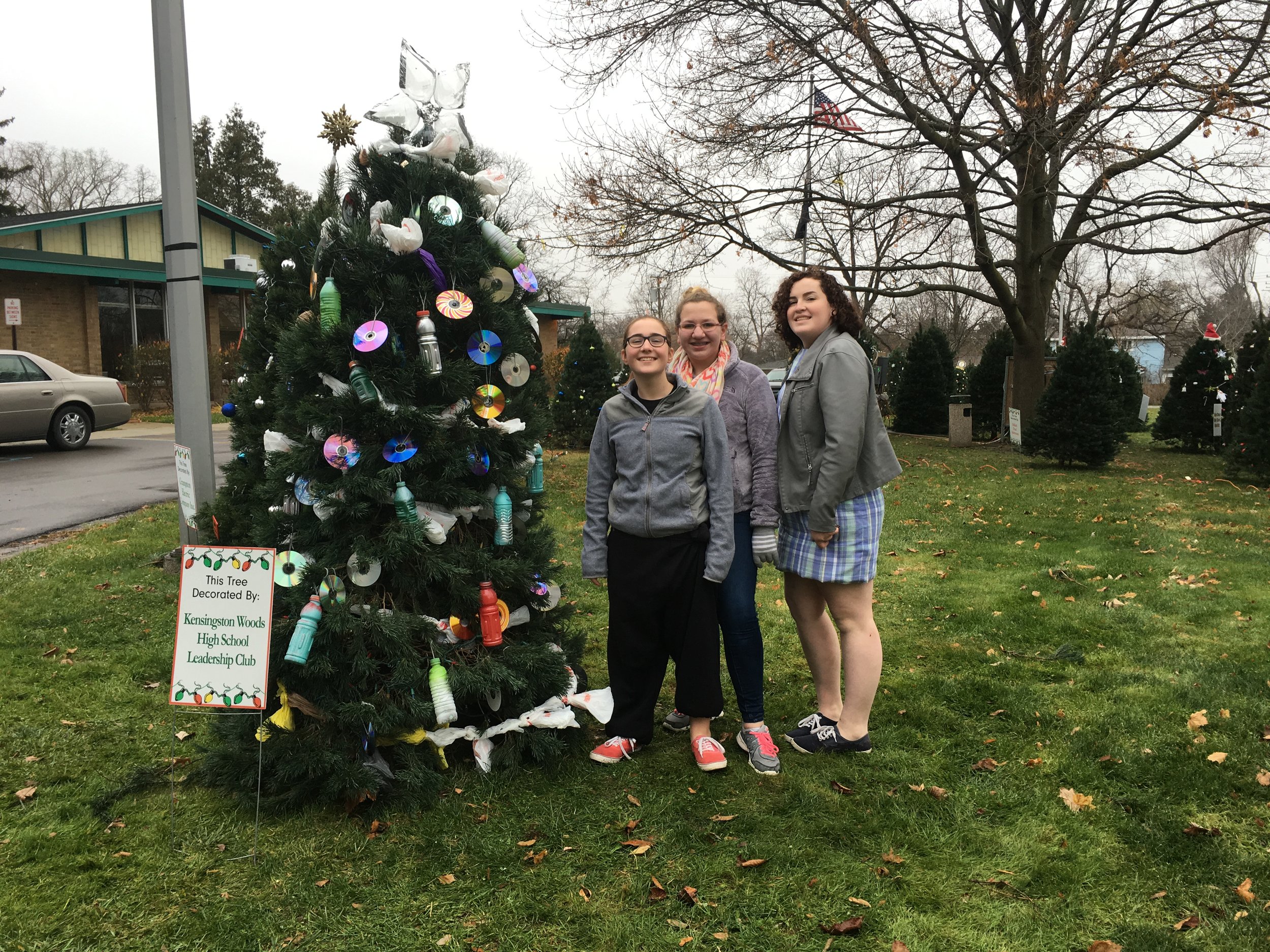 students standing next to Christmas tree