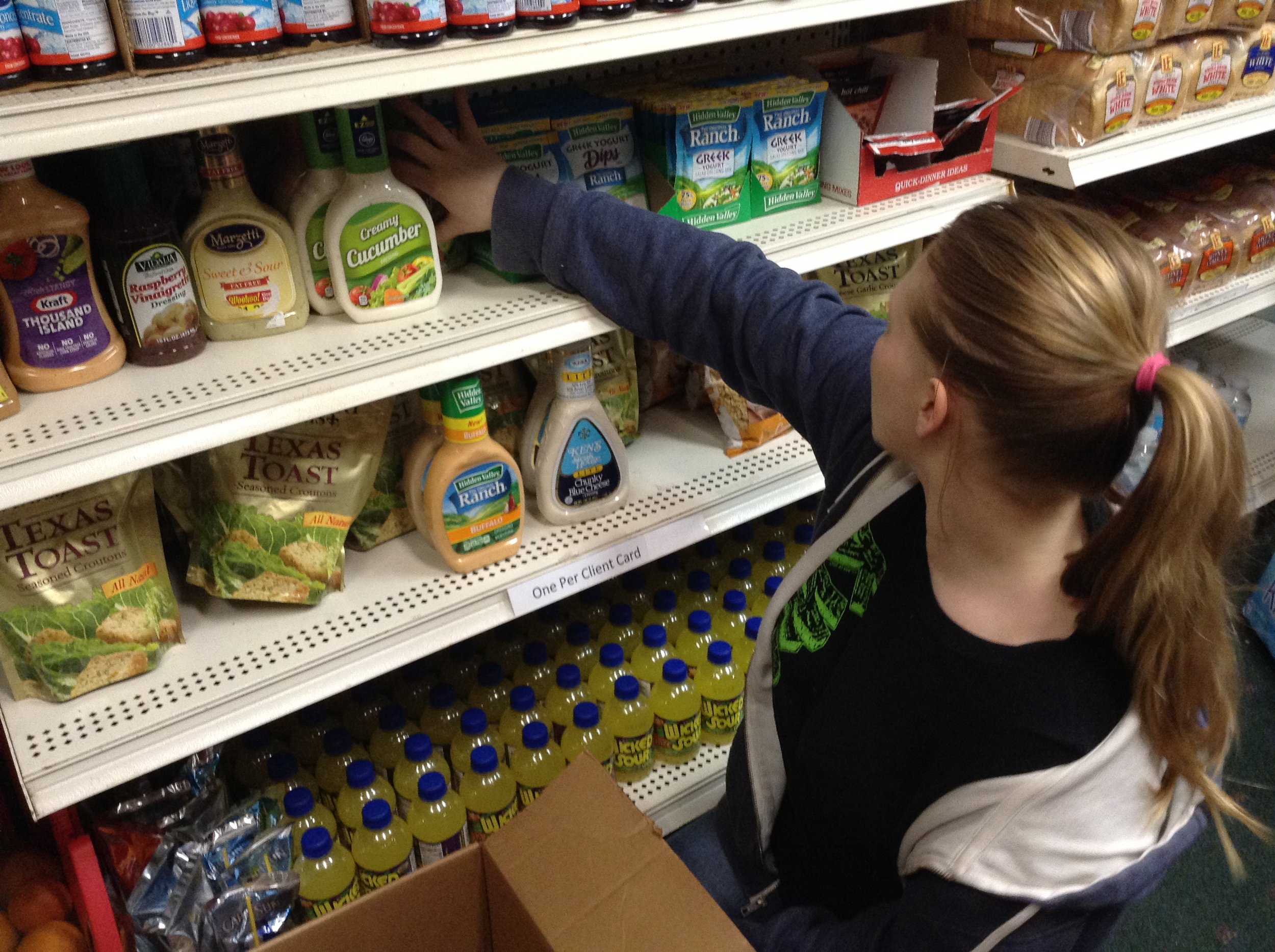 student stocking shelves with non-perishable food items