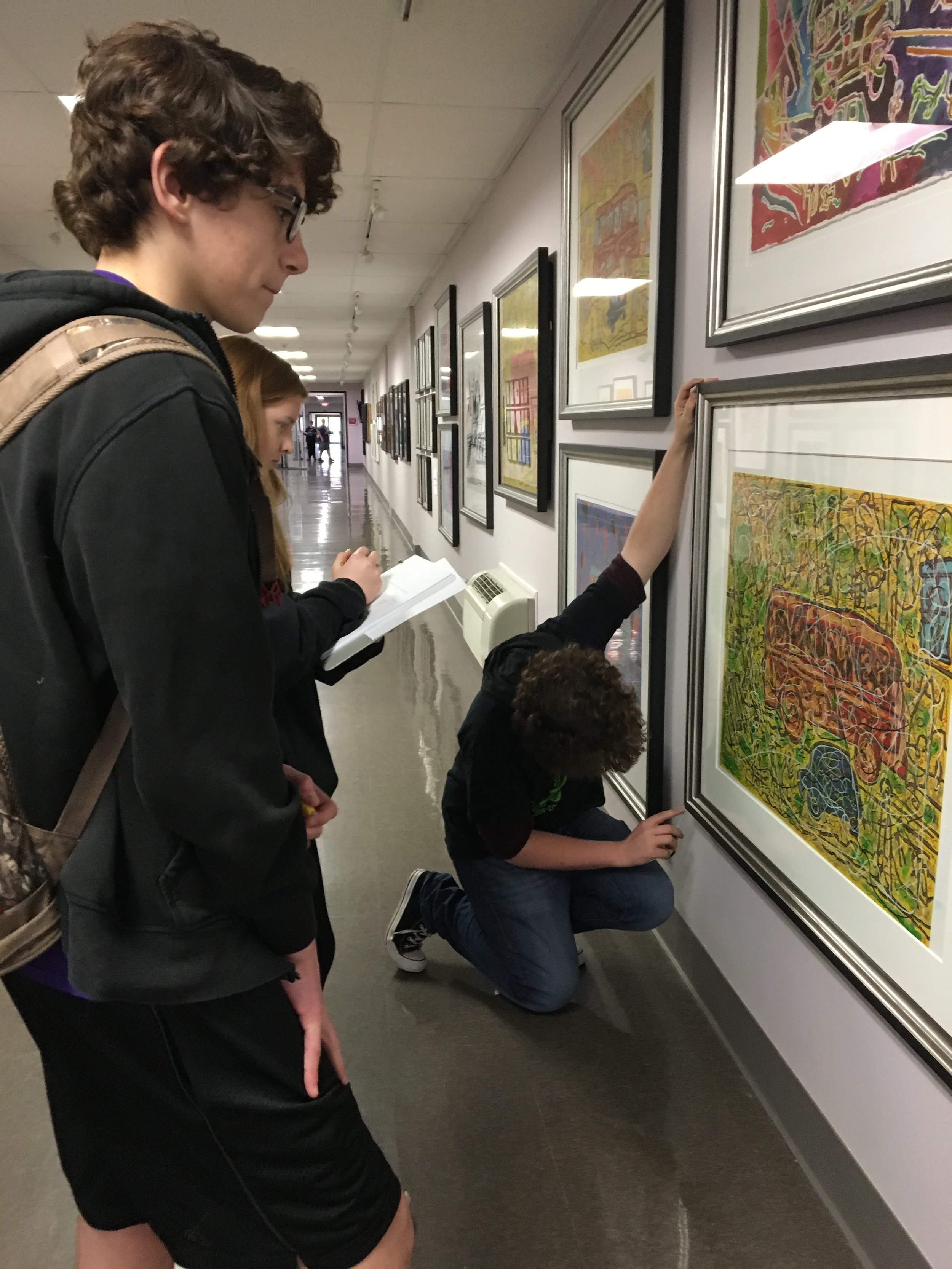 students hanging artwork on a wall