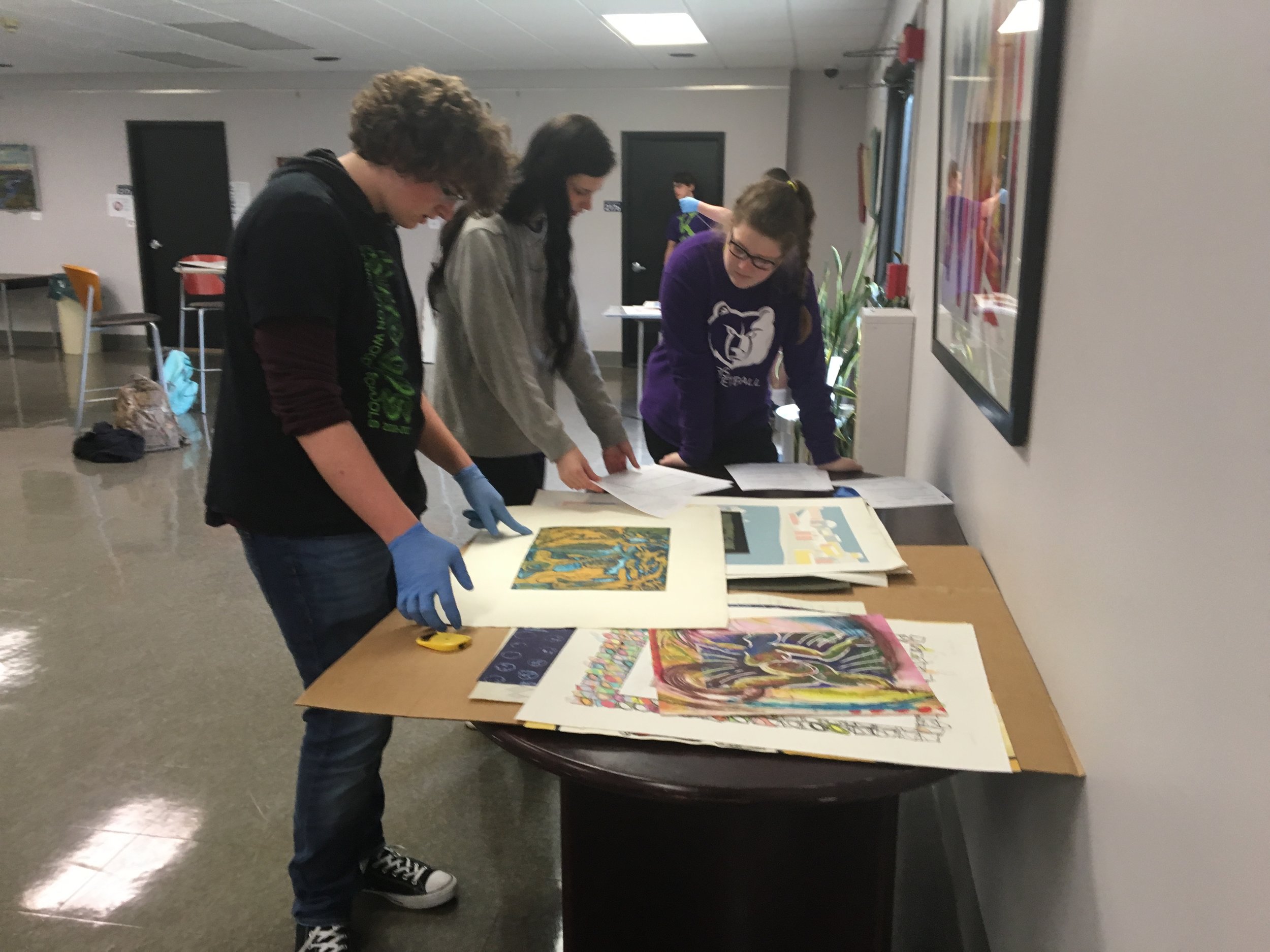 group of students sorting artwork to display