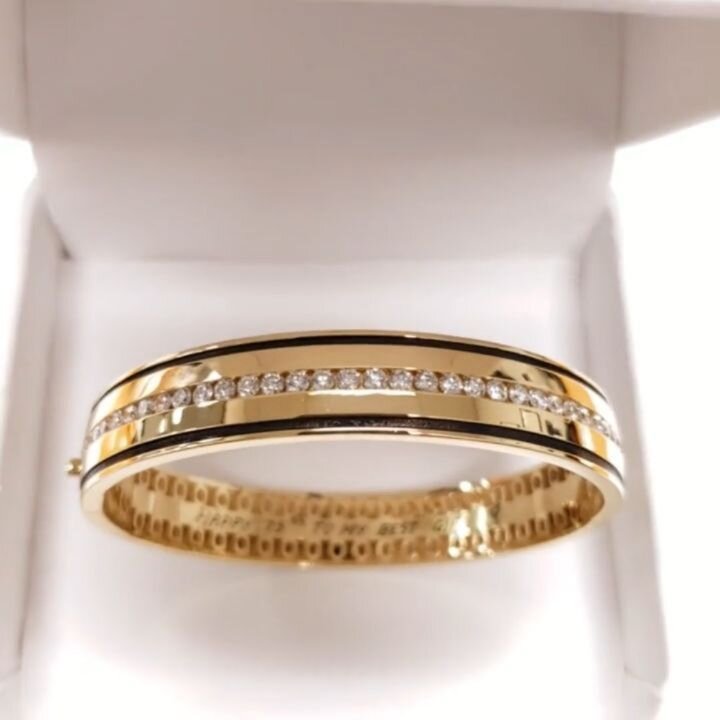 Exquisite, custom designed, 75th birthday present for a terrific woman.
18k yellow gold bangle bracelet with 4.45 carats total weight of ideal cut diamonds, 2 rows of black enameling and a black diamond in the plunger of the clasp with hand engraving