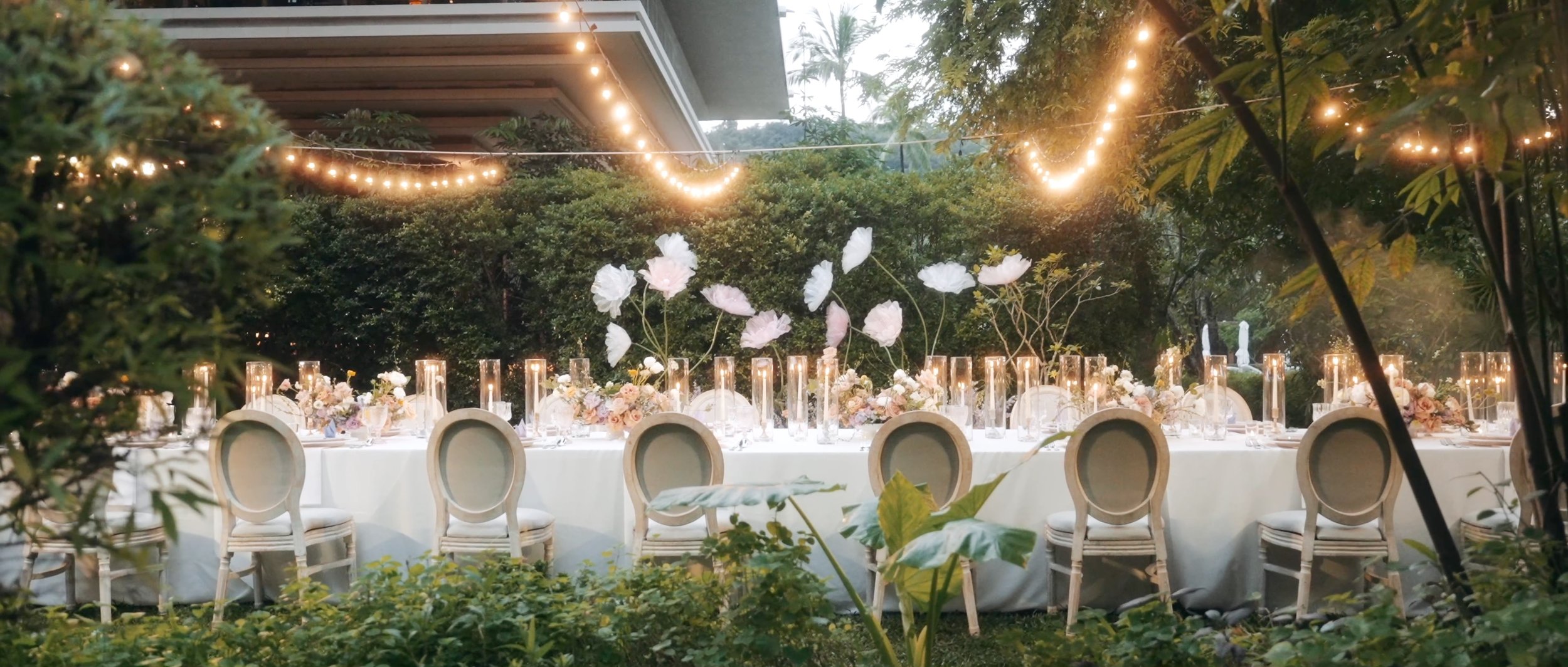 An elegant dinner table setup at the Rosewood Phuket reception, featuring lights and floral arrangements under the night sky.