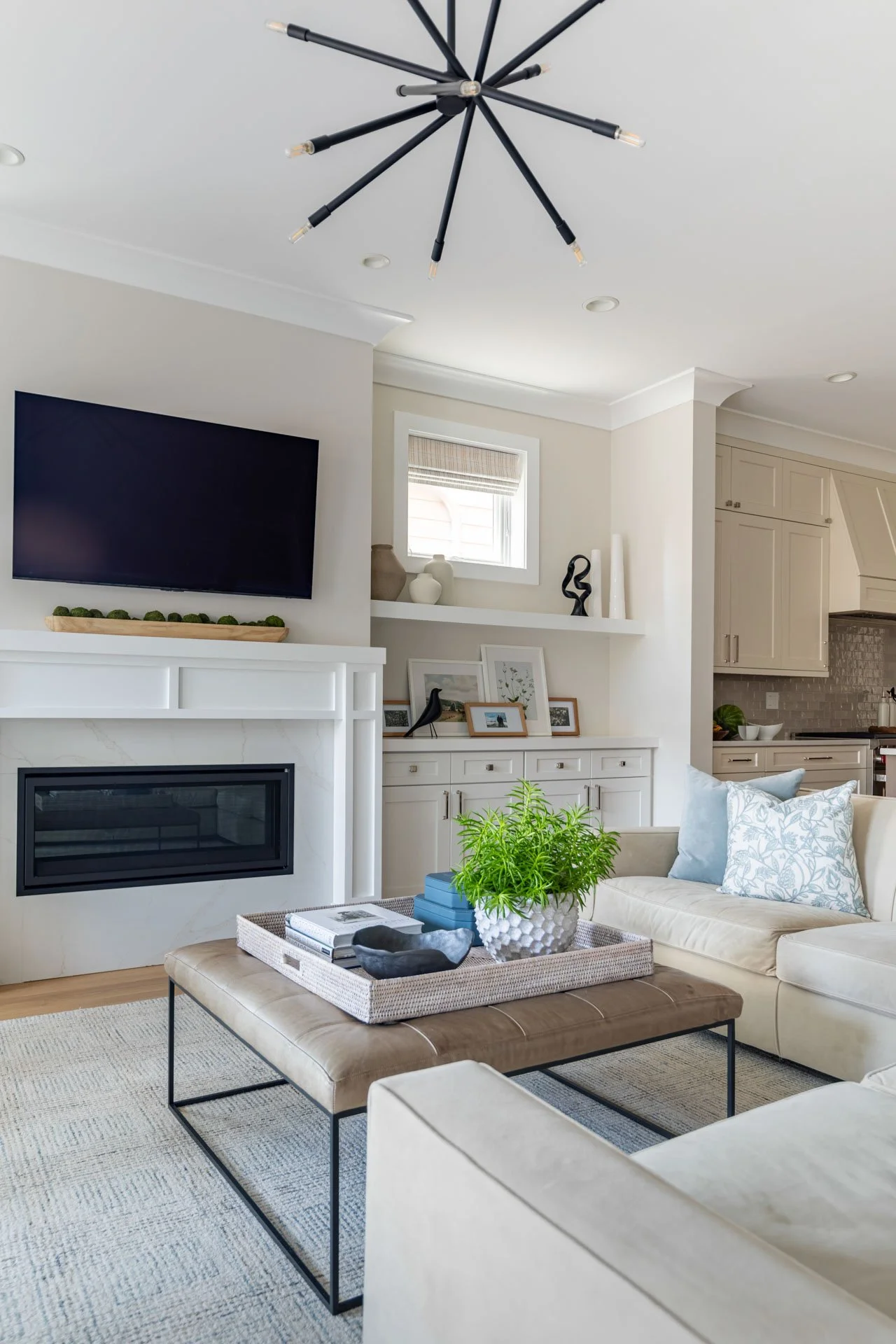 Detail view of Roscoe Village Chicago family room featuring fireplace with built-ins, modern chandelier, and styled coffee table with greenery, designed by Wendy Nobriga Interiors.