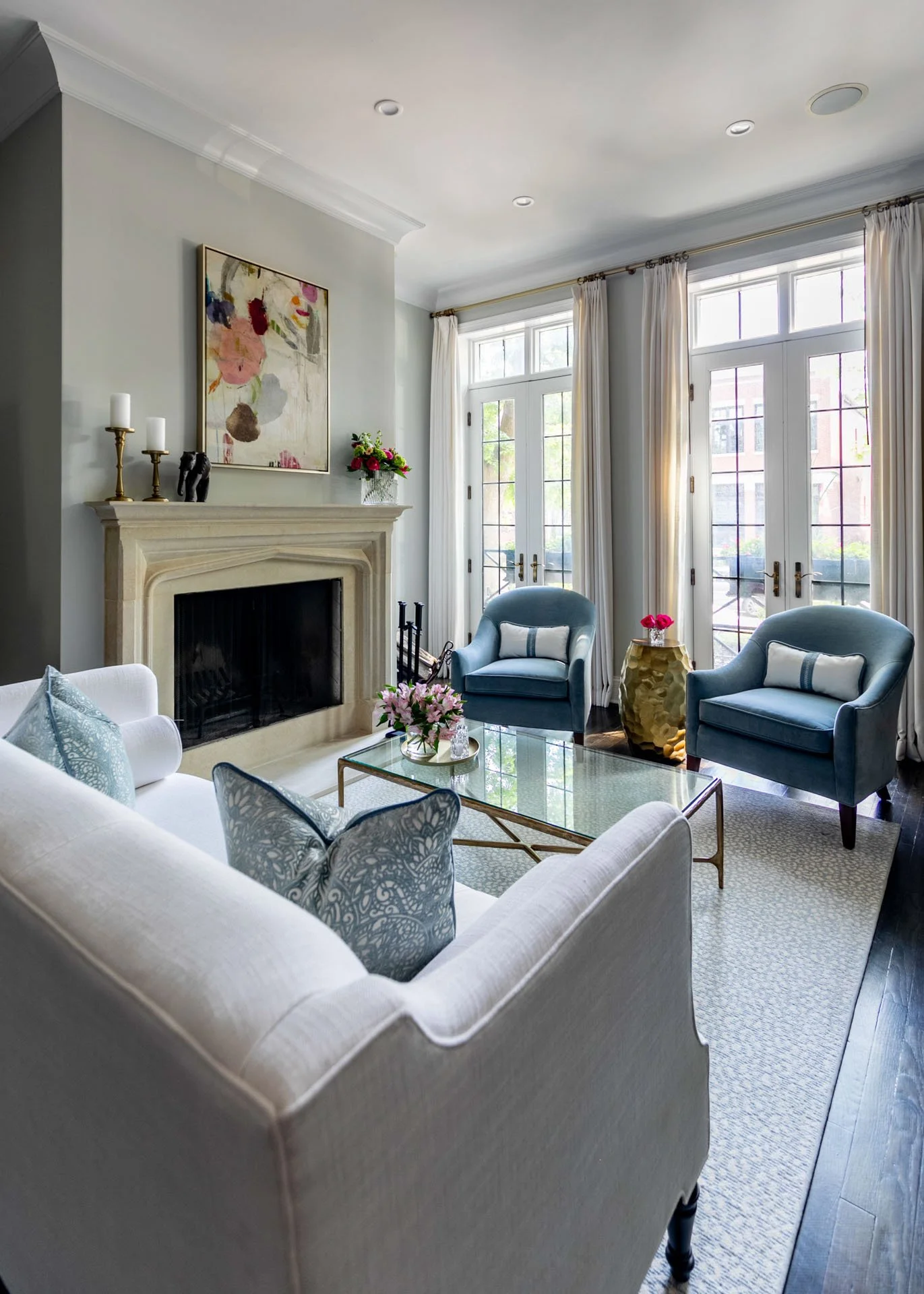 Lincoln Park Chicago living room with white sofa blue accent chairs glass coffee table and fireplace by Wendy Nobriga Interiors
