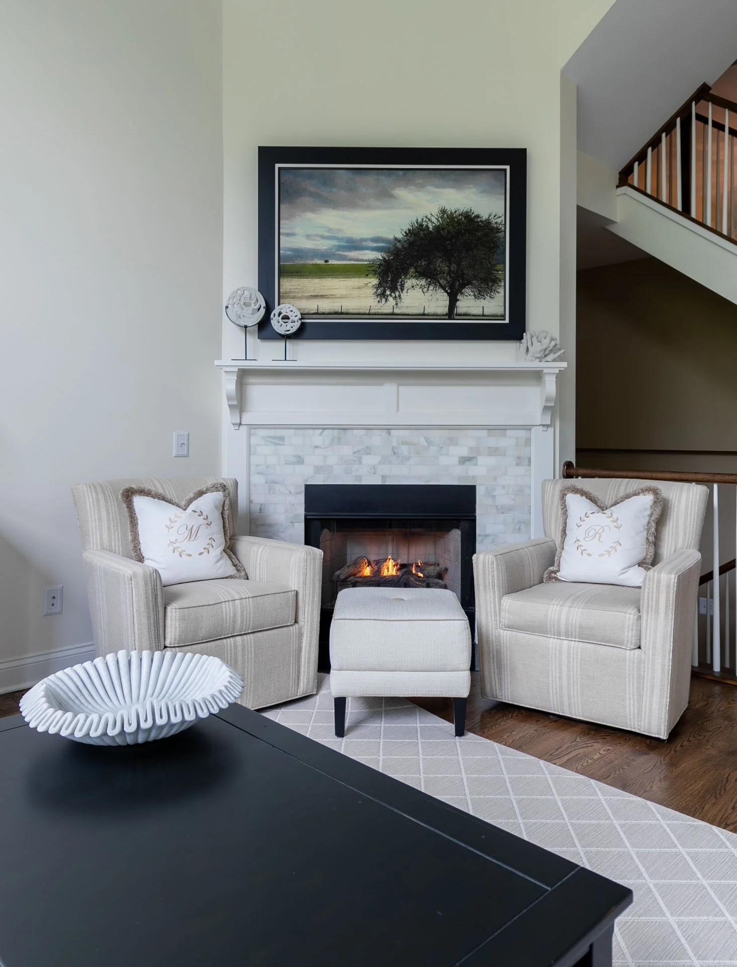 Des Plaines IL living room fireplace with striped armchairs, monogrammed pillows, and marble surround designed by Wendy Nobriga Interiors