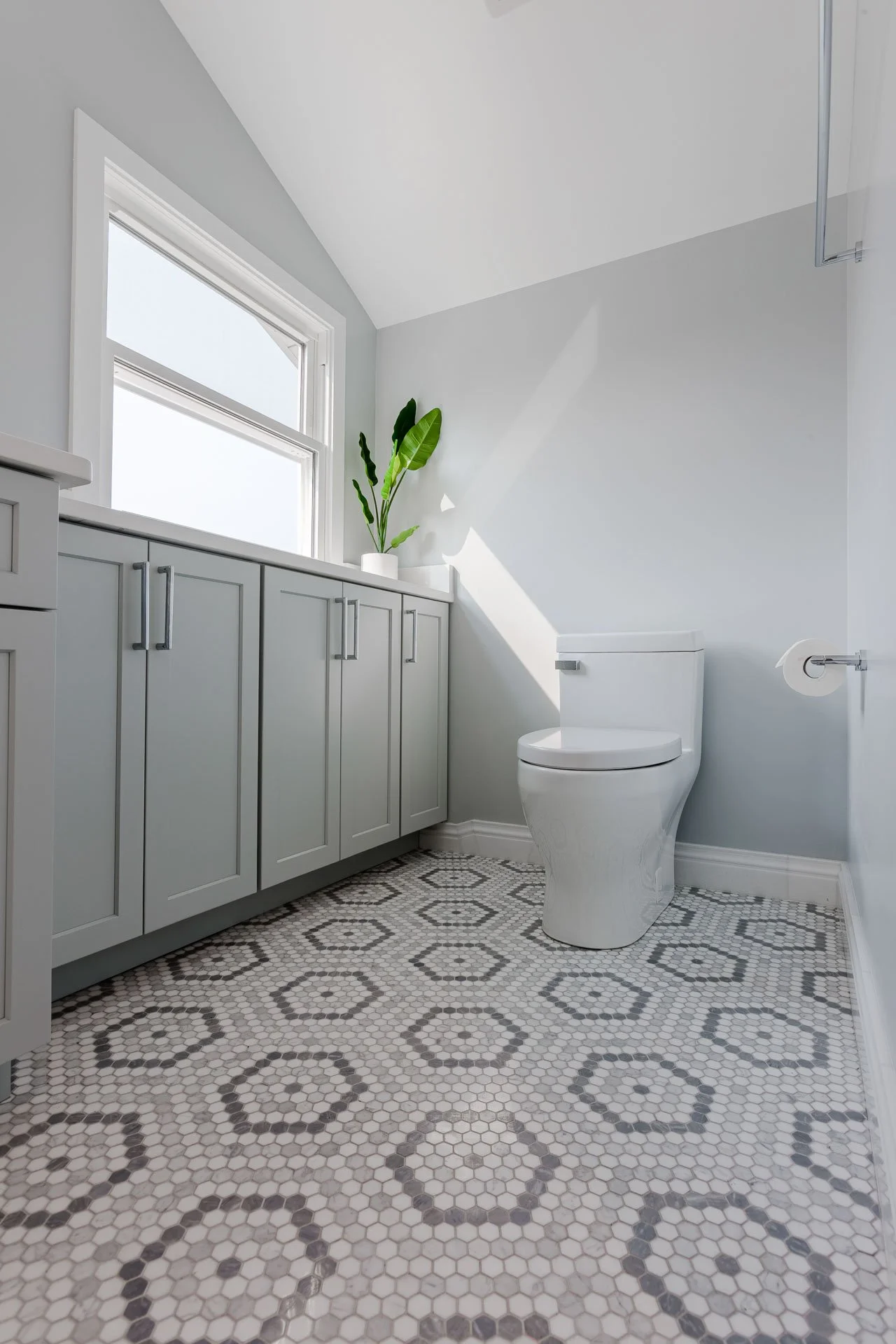 North Center Chicago bathroom with marble mosaic hexagon floor, gray cabinetry, white toilet, and modern chrome hardware, designed by Wendy Nobriga Interiors