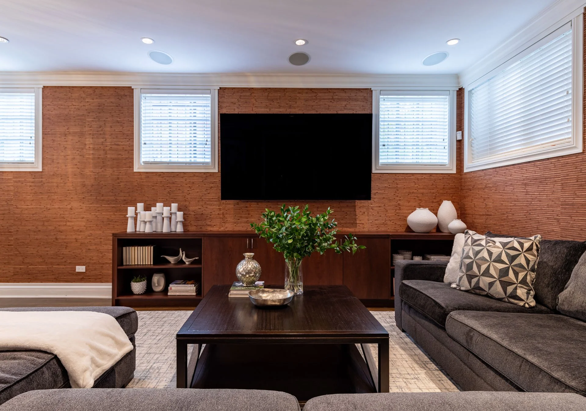 Straight-on view of Roscoe Village Chicago basement family room with TV, wood console, and modern sectional, designed by Wendy Nobriga Interiors.
