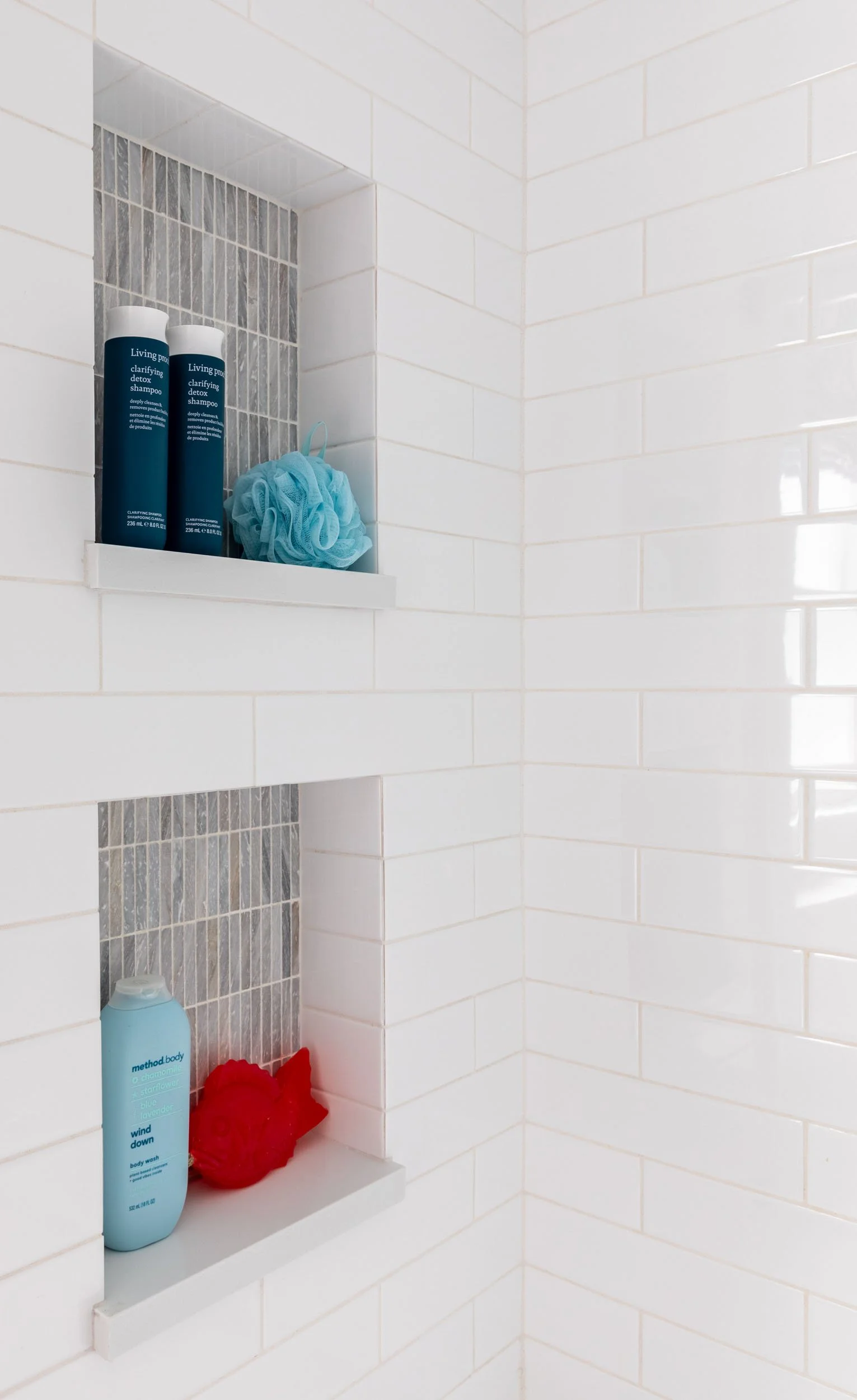 Kids bathroom shower niche in Northbrook, Illinois with white subway tile, gray mosaic accent tile, and built-in shelving. Design by Wendy Nobriga Interiors.
