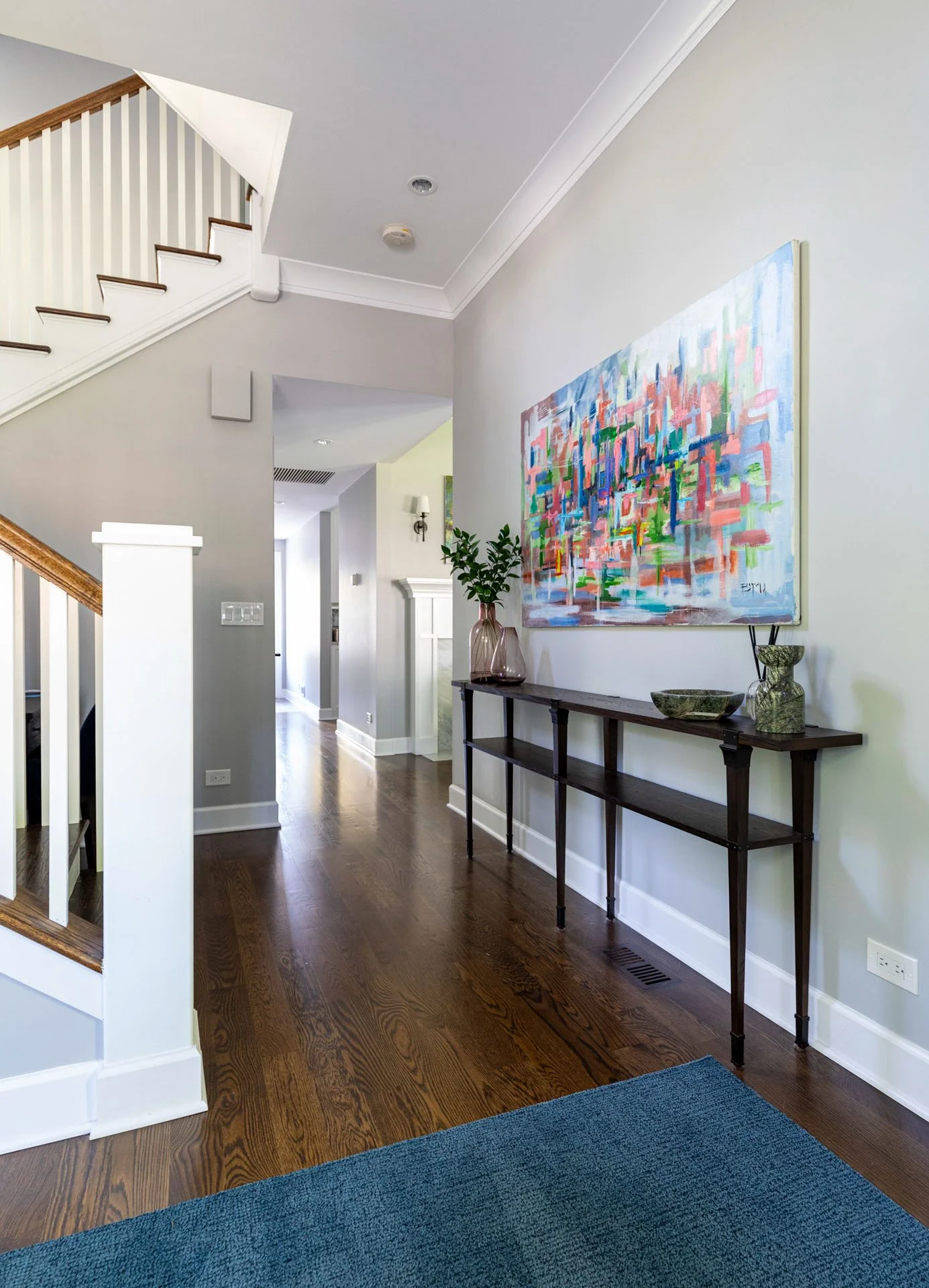 La Grange foyer view into hallway with dark wood console table, abstract artwork, and staircase detail, design by Wendy Nobriga Interiors.