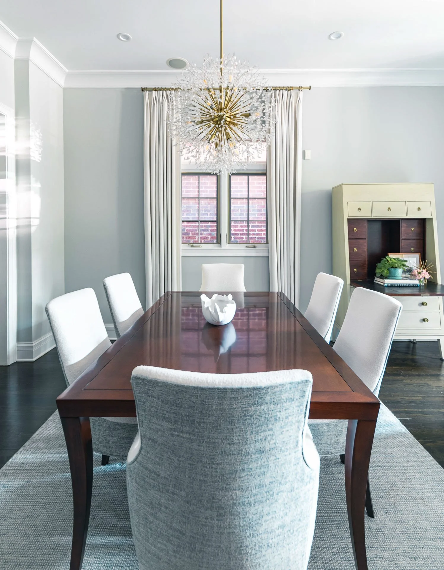 Lincoln Park Chicago dining room with crystal chandelier over wood dining table and upholstered chairs designed by Wendy Nobriga Interiors