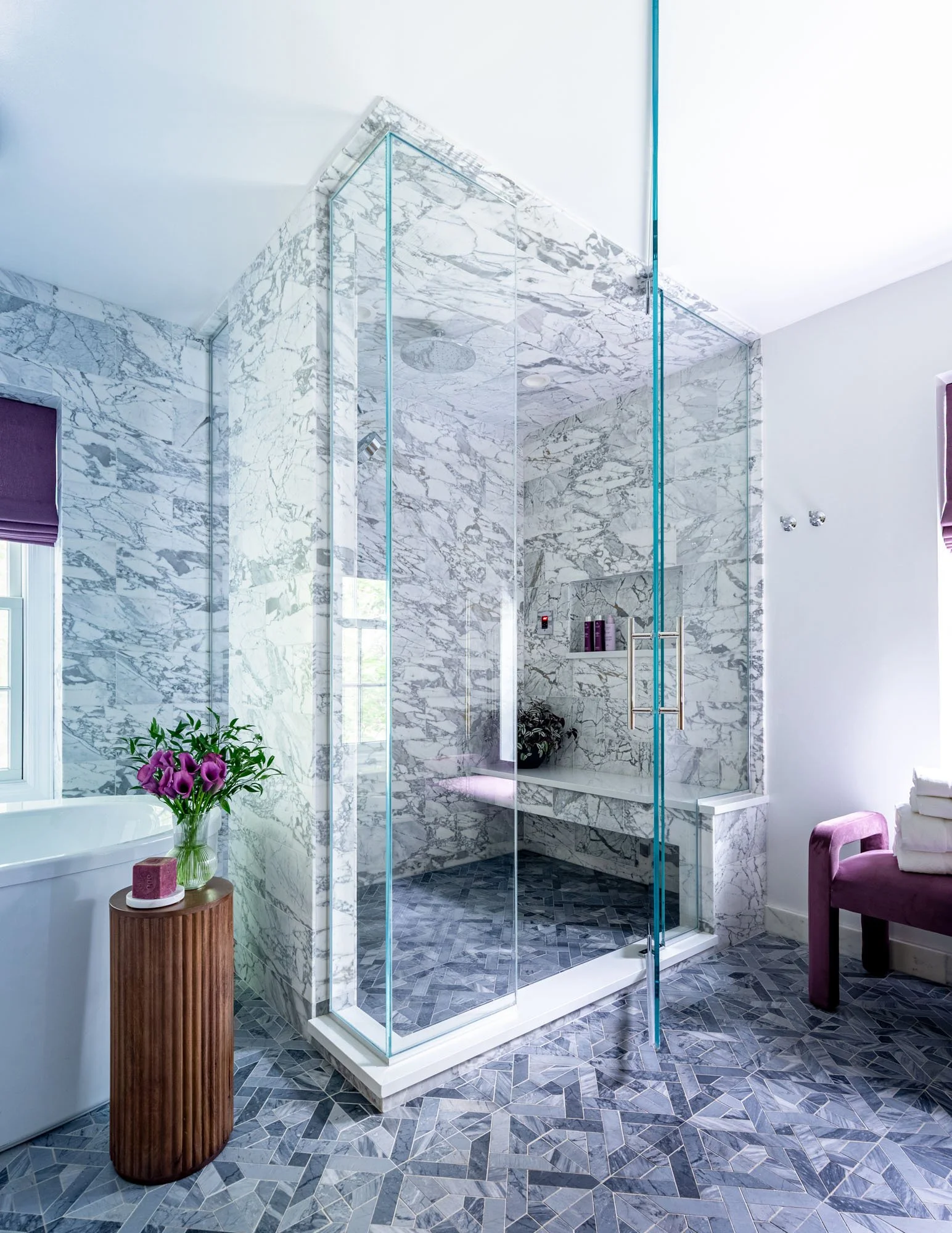 Luxury primary bathroom in Northbrook, Illinois with marble shower and frameless glass enclosure. Design by Wendy Nobriga Interiors.