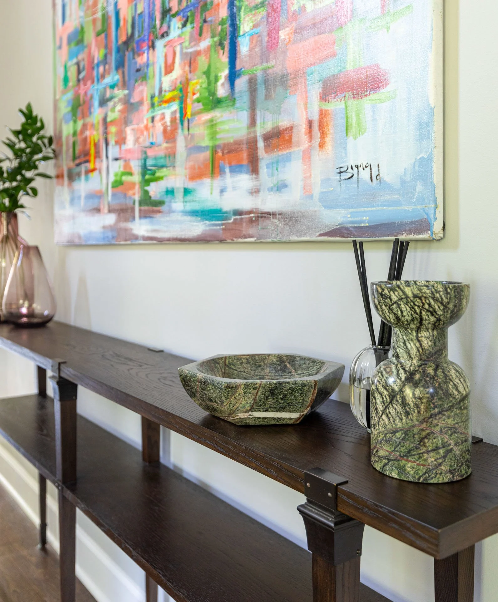 La Grange foyer console table styled with marble vase, green stone bowl, pink glass vase, and abstract artwork above, design by Wendy Nobriga Interiors.