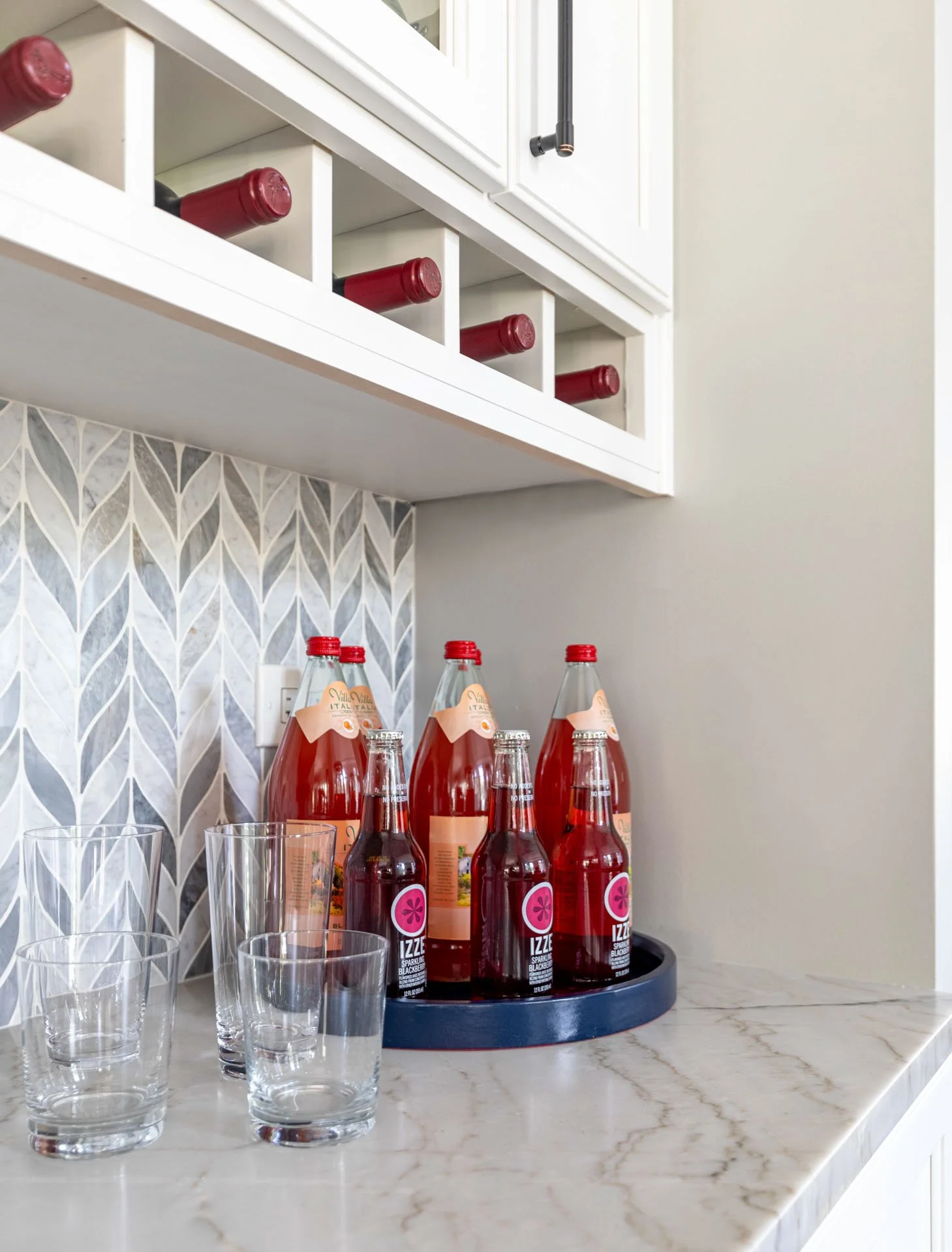 La Grange IL kitchen bar countertop styled with sparkling drinks, wine bottles, and glassware on quartzite surface by Wendy Nobriga Interiors.