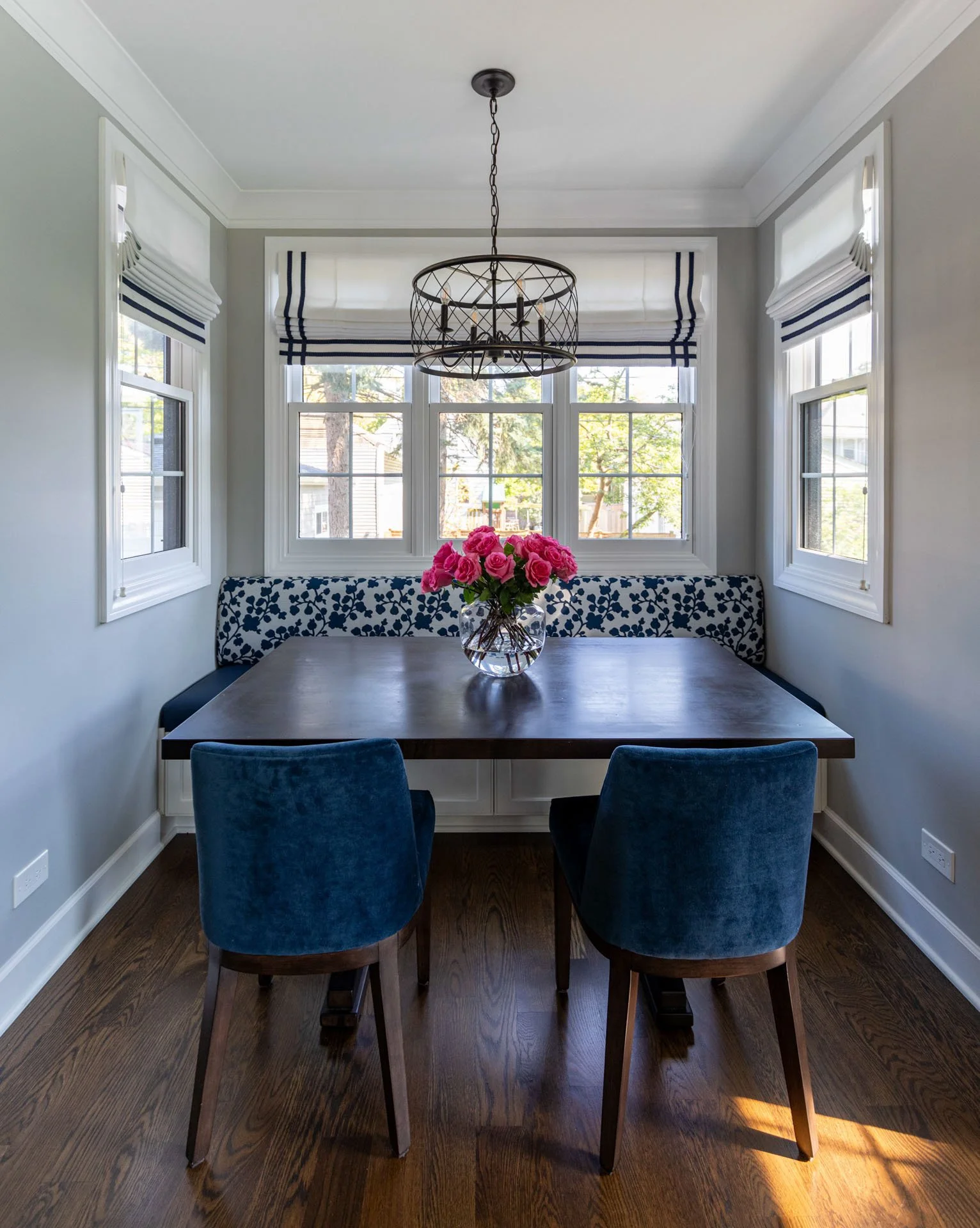 La Grange IL kitchen breakfast nook with custom blue floral banquette, wood table, velvet chairs, and chandelier by Wendy Nobriga Interiors.