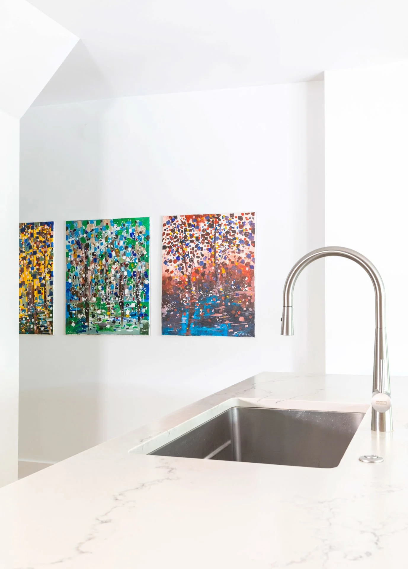 Wildwood Chicago IL kitchen sink view with quartz countertop, stainless steel faucet, and colorful modern artwork on the wall, designed by Wendy Nobriga Interiors.