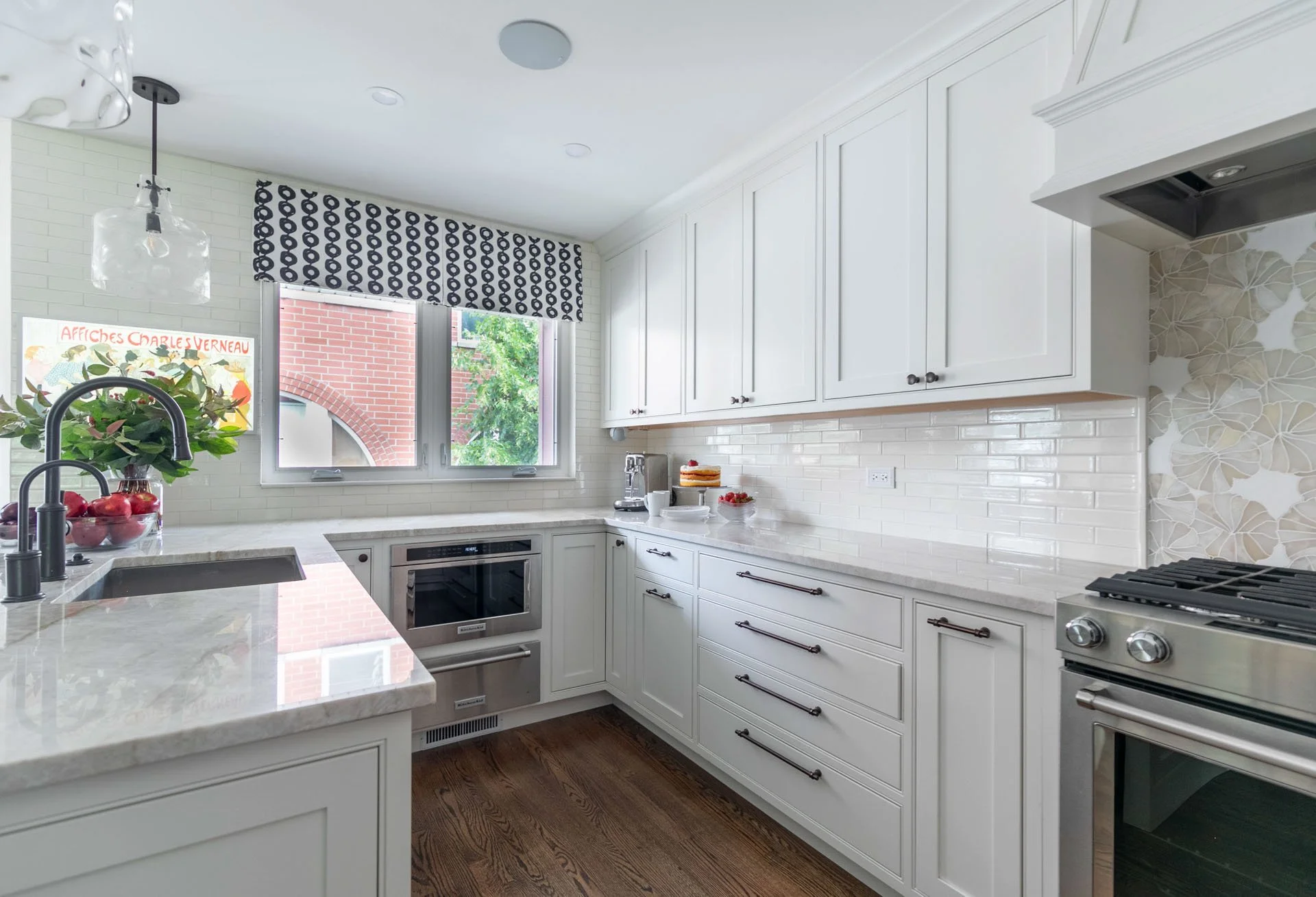 Des Plaines IL kitchen with white cabinetry, quartzite peninsula, stainless steel appliances, and floral backsplash by Wendy Nobriga Interiors