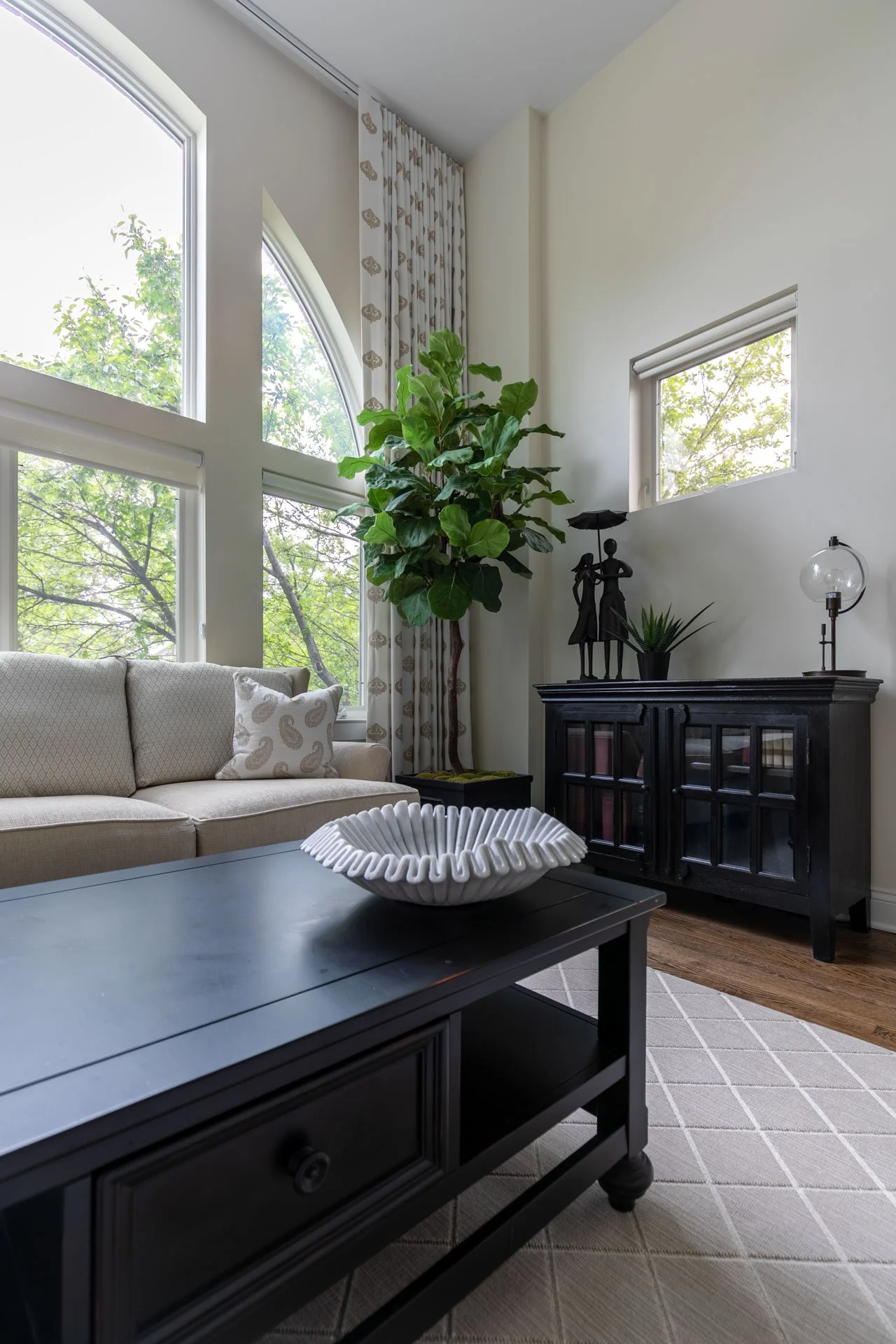 Des Plaines IL living room with black coffee table, sculptural bowl, beige sofa, fiddle leaf fig, and black console cabinet styled by Wendy Nobriga Interiors