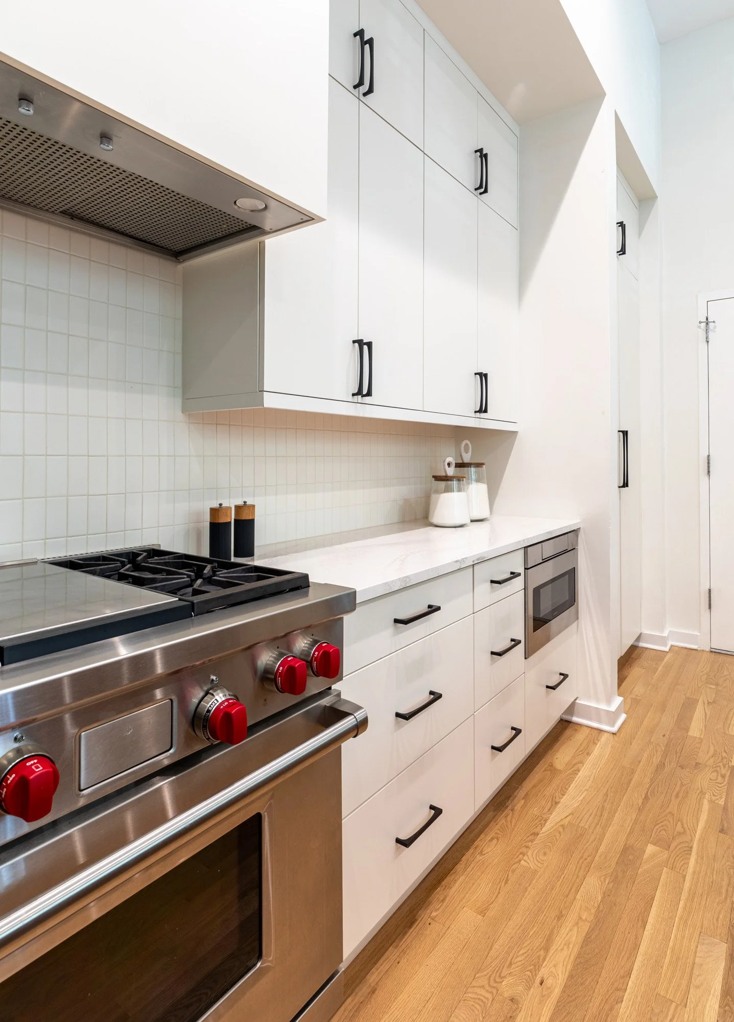 Lincoln Park, Chicago modern kitchen designed by Wendy Nobriga Interiors featuring custom white cabinetry, quartz countertops, abundant storage, and a streamlined workspace.