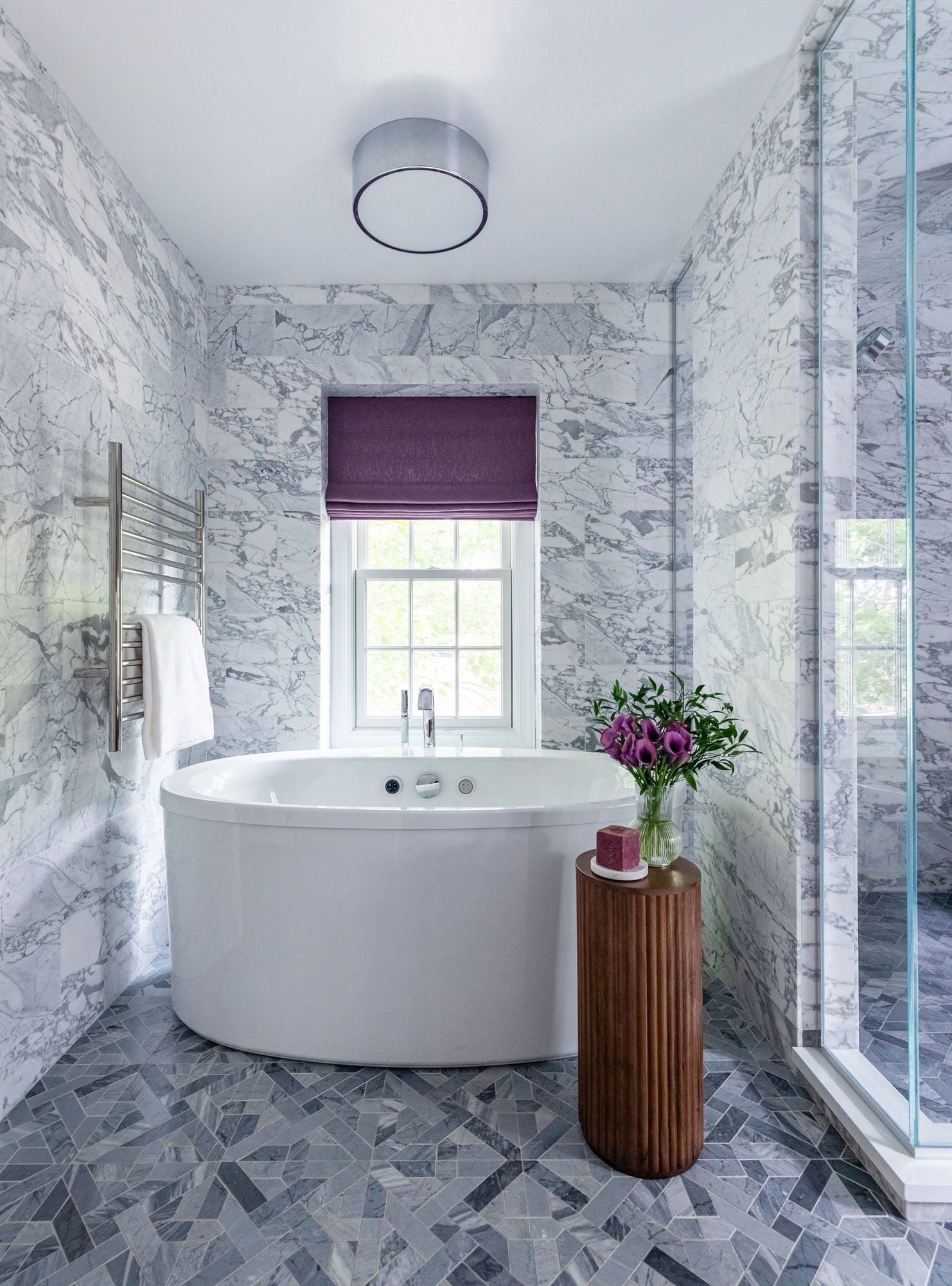 Primary bathroom in Northbrook, Illinois with freestanding soaking tub and marble tile walls. Design by Wendy Nobriga Interiors.