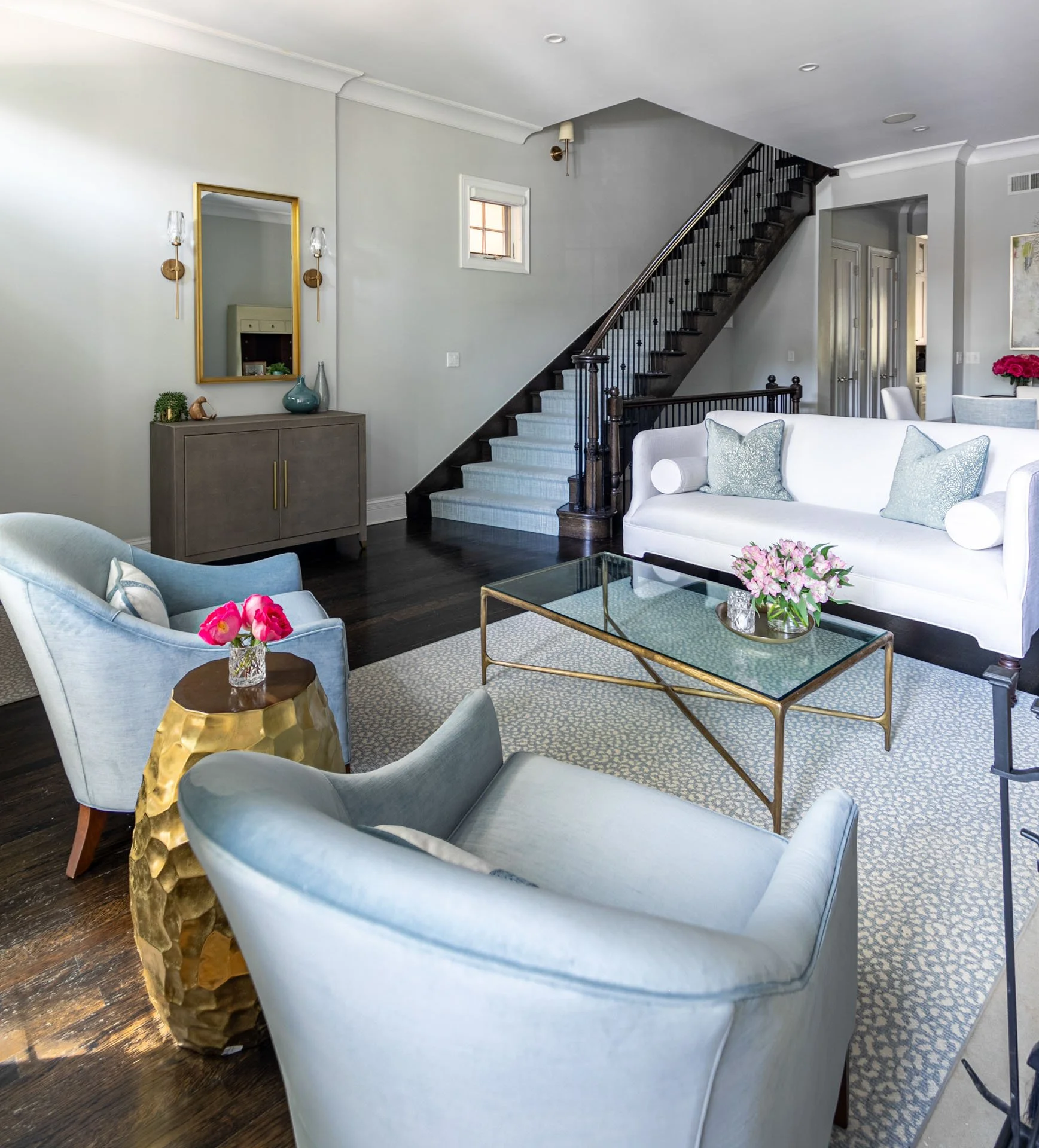 Lincoln Park Chicago living room with white sofa blue chairs glass coffee table and staircase by Wendy Nobriga Interiors