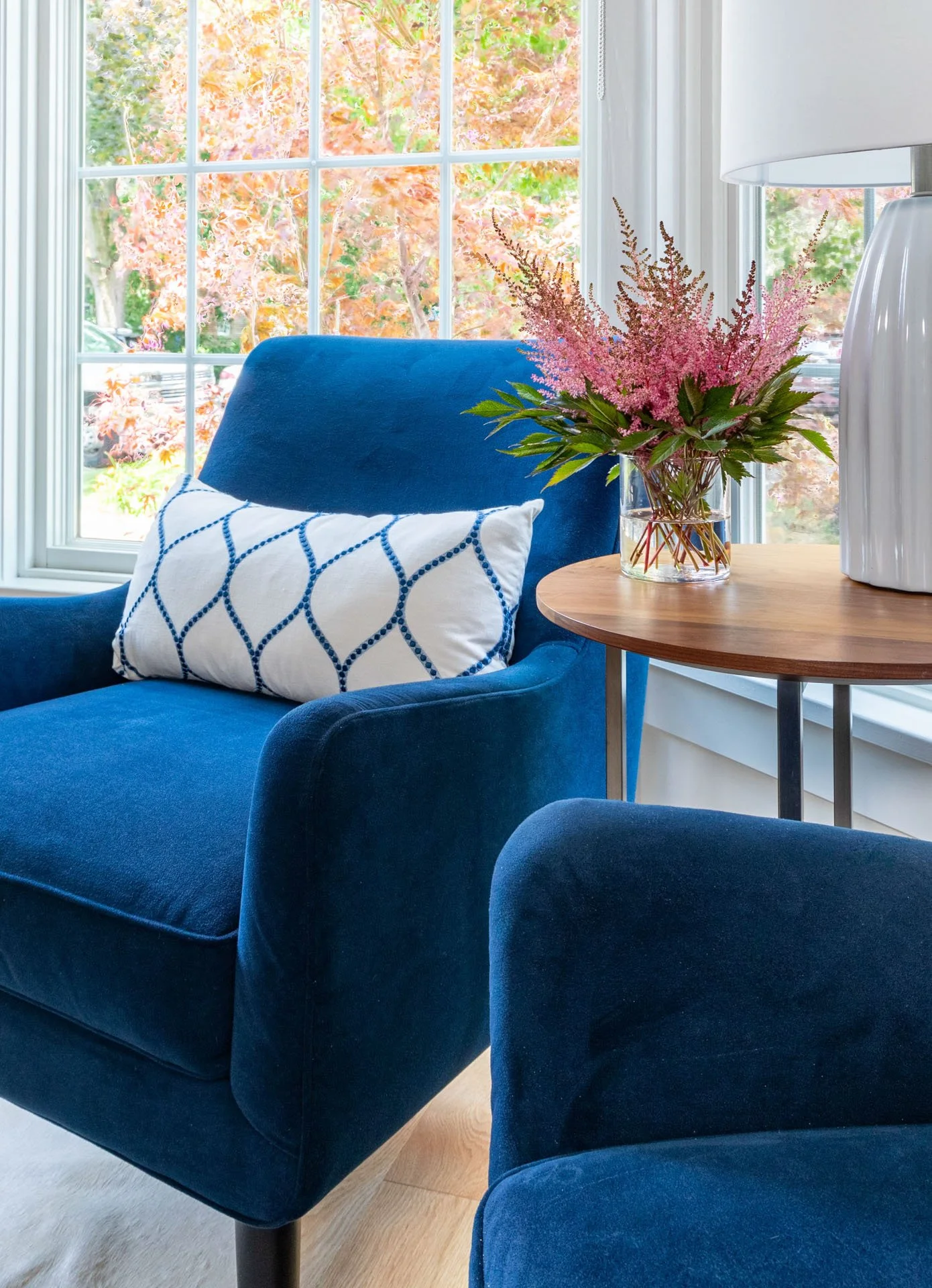 Wildwood Chicago IL home office seating close-up with navy armchair, white patterned pillow, wood side table, and vase of pink flowers styled by Wendy Nobriga Interiors.