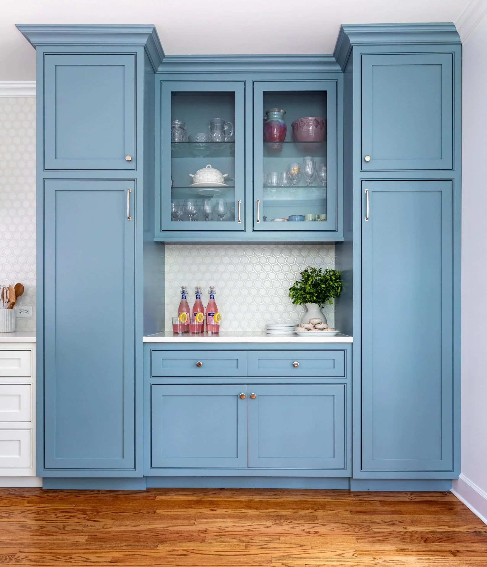 Lake Forest IL kitchen with custom blue cabinetry, glass-front upper cabinets, white backsplash, and quartz countertop, designed by Wendy Nobriga Interiors.