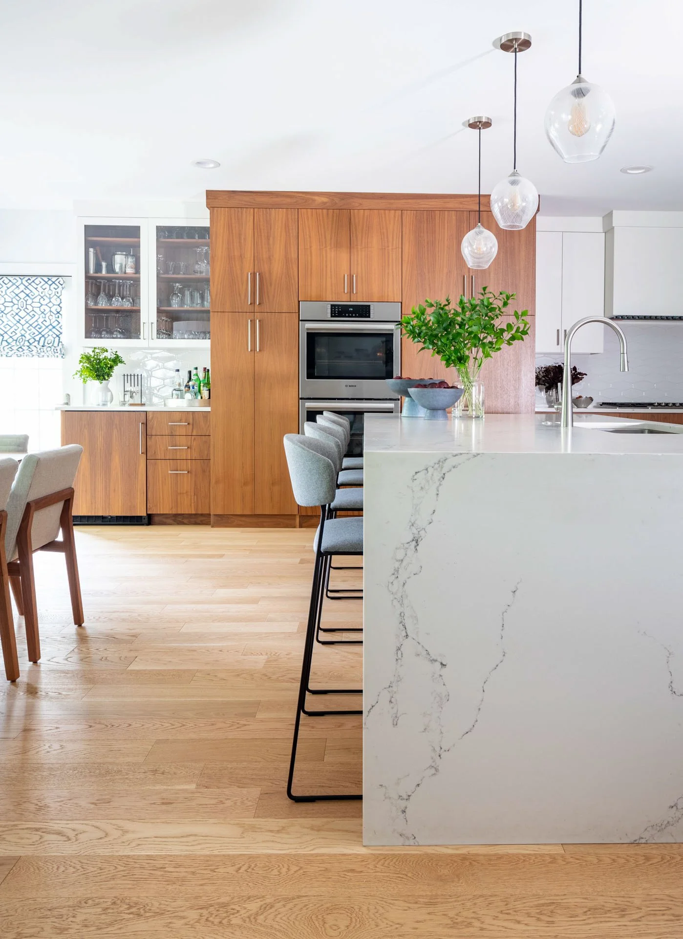 Wildwood Chicago IL kitchen island with quartz waterfall countertop, walnut wood cabinetry, pendant lighting, and seating, designed by Wendy Nobriga Interiors.