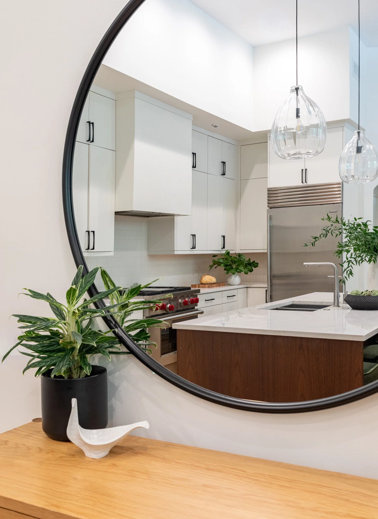 Lincoln Park, Chicago modern kitchen entry view designed by Wendy Nobriga Interiors showcasing the open-concept kitchen through the entry mirror.