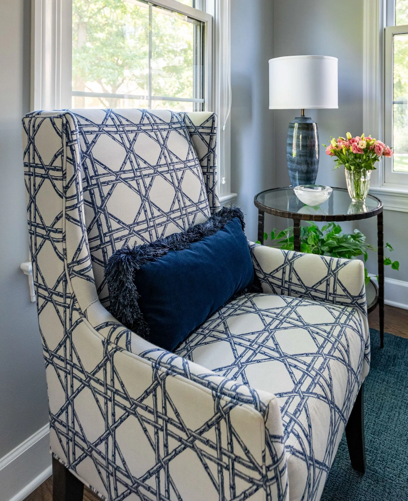 La Grange foyer patterned accent chair with blue lumbar pillow next to round side table with lamp and flowers, design by Wendy Nobriga Interiors.