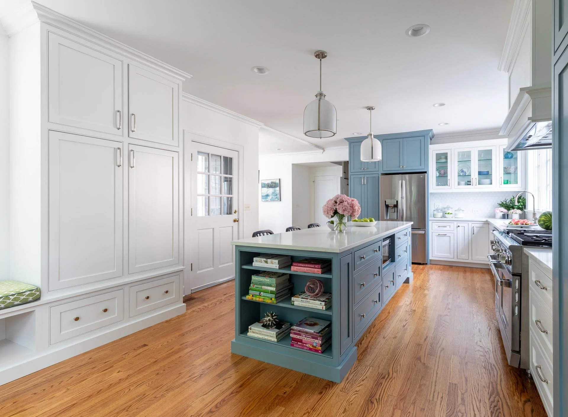 Transitional kitchen in Lake Forest IL with blue cabinetry, a white quartz island, stainless steel appliances, and black counter stools, designed by Wendy Nobriga Interiors.