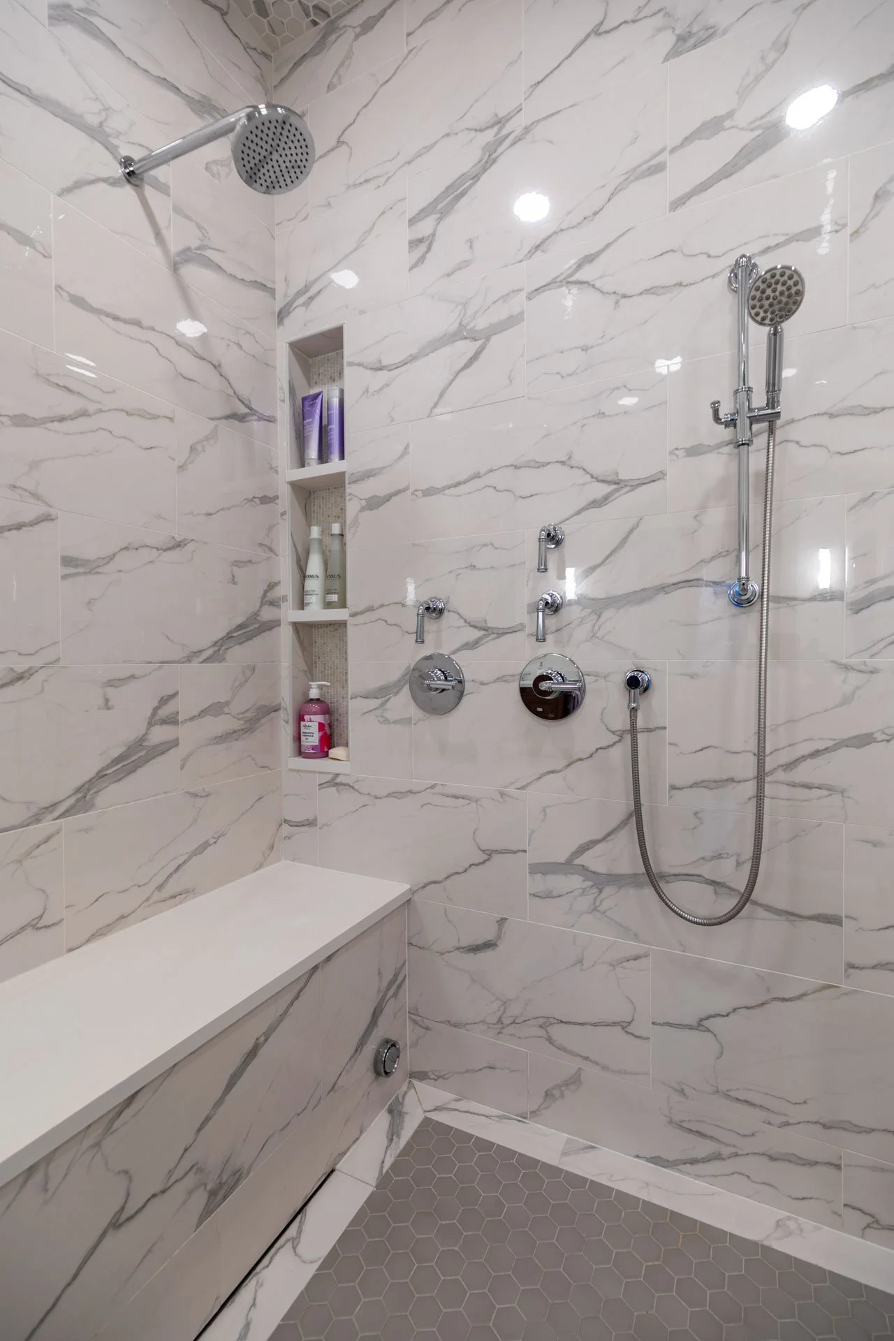 Lake View Chicago primary bathroom wet room with marble-look porcelain tile, built-in bench, and rain shower, designed by Wendy Nobriga Interiors