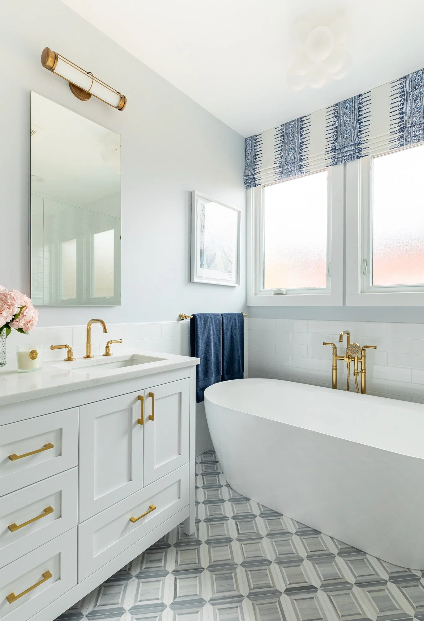 Custom white vanity and freestanding soaking tub in a North Edgebrook Chicago primary bathroom featuring marble mosaic flooring and brass fixtures, designed by Wendy Nobriga Interiors.