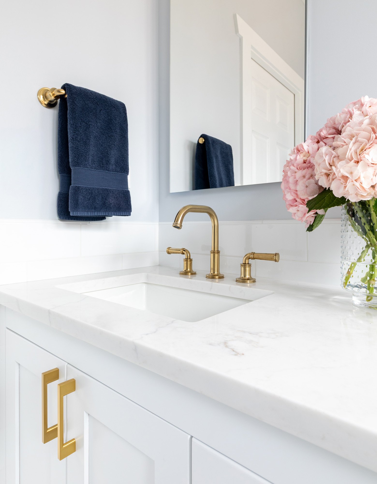 Quartz countertop with an undermount sink, brass faucet, and custom white cabinetry in a North Edgebrook Chicago primary bathroom, designed by Wendy Nobriga Interiors.