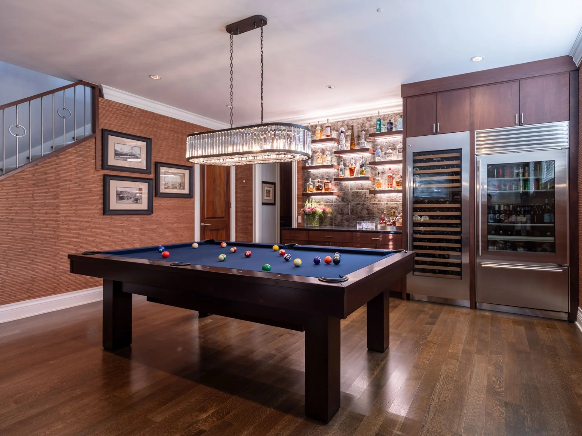 Wide view of Roscoe Village Chicago basement bar with pool table, crystal chandelier, and wine storage, designed by Wendy Nobriga Interiors.