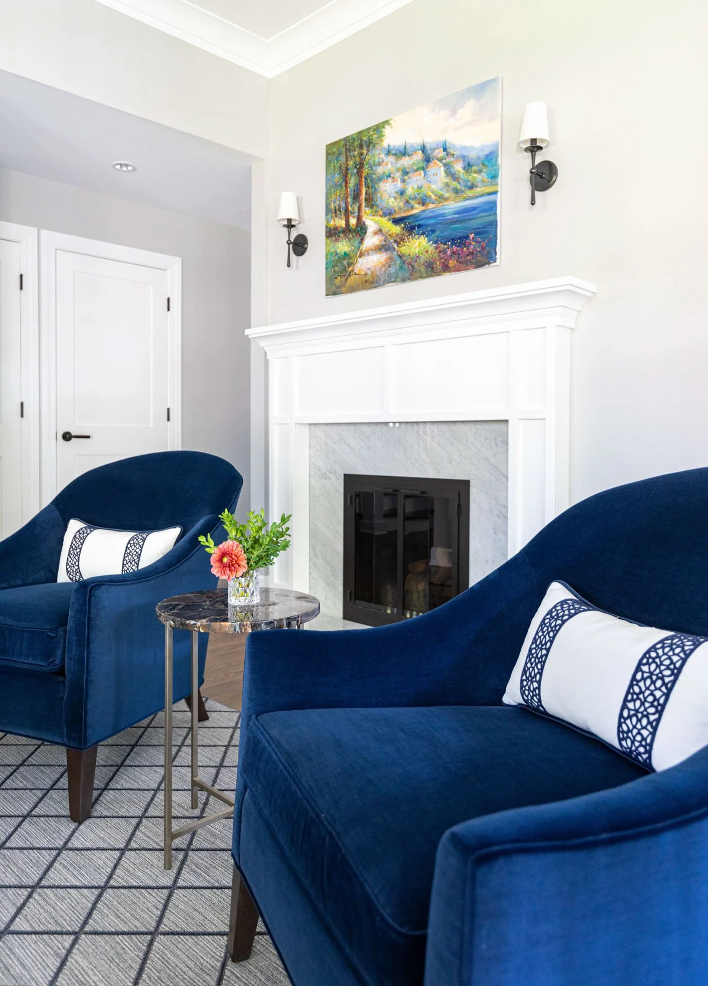 La Grange IL living room featuring white fireplace, navy blue chairs, and colorful landscape artwork styled by Wendy Nobriga Interiors