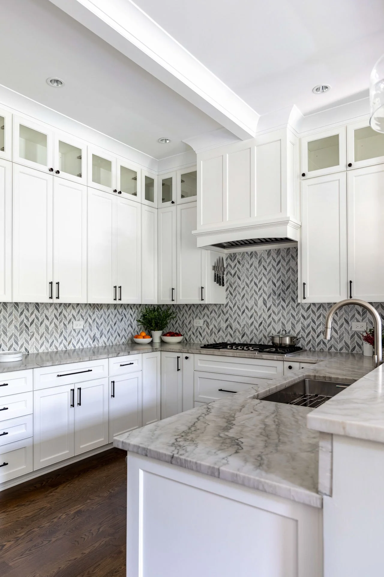 La Grange IL kitchen with white shaker cabinets, quartzite countertops, chevron backsplash, and stainless steel appliances by Wendy Nobriga Interiors.