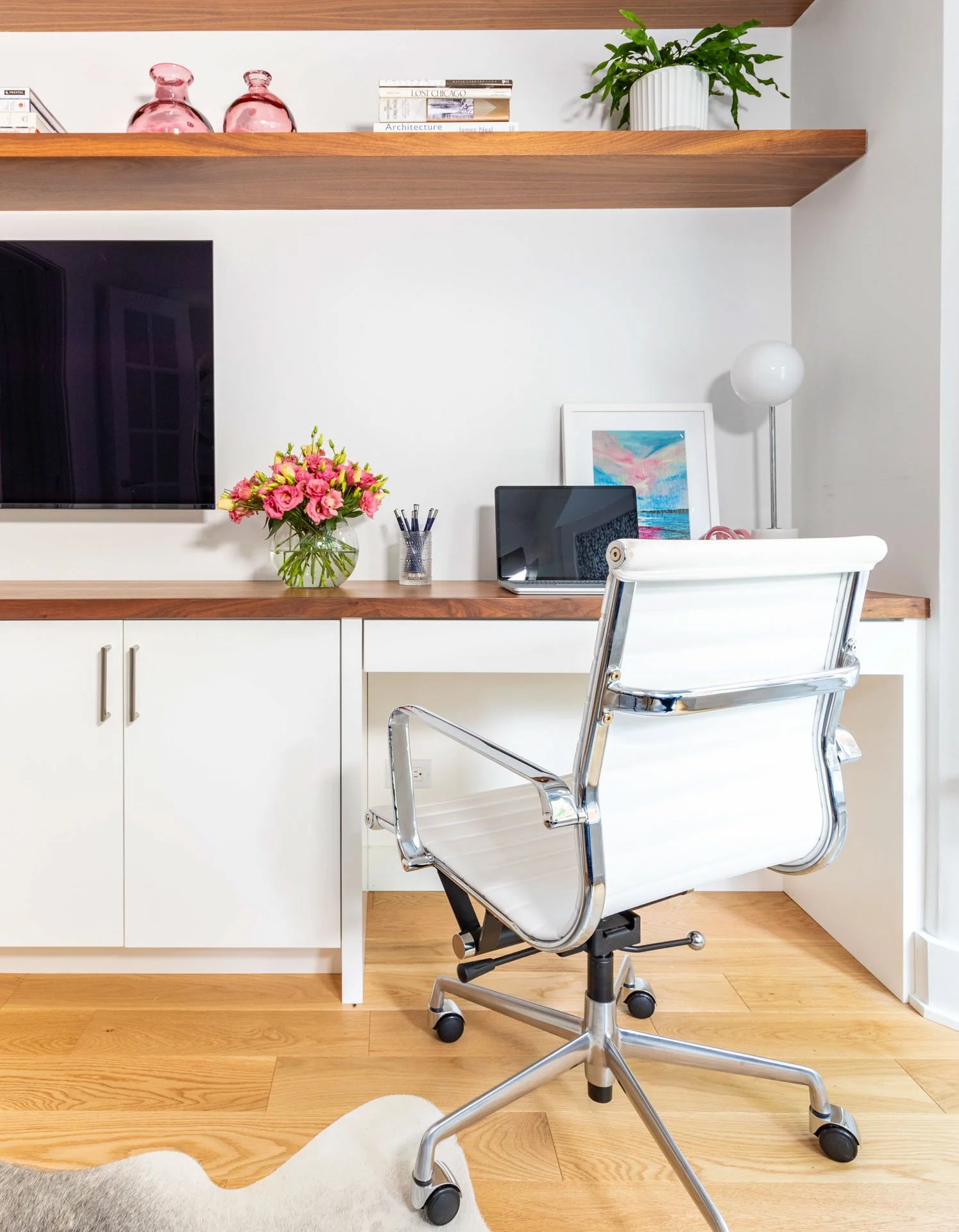 Wildwood Chicago IL home office desk detail with white swivel chair, floating shelves, fresh flowers, and modern decor styled by Wendy Nobriga Interiors.