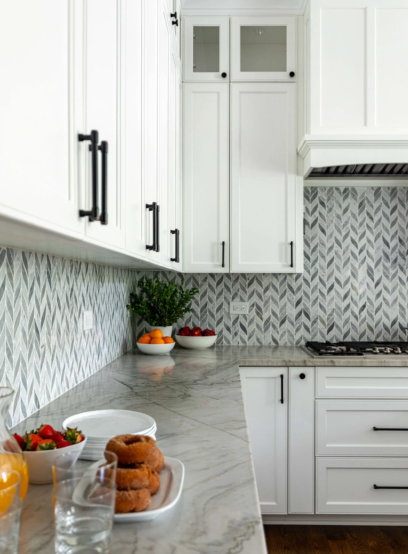 Quartzite kitchen countertop in La Grange IL home with white cabinets, chevron backsplash, and styled fruit bowls by Wendy Nobriga Interiors.