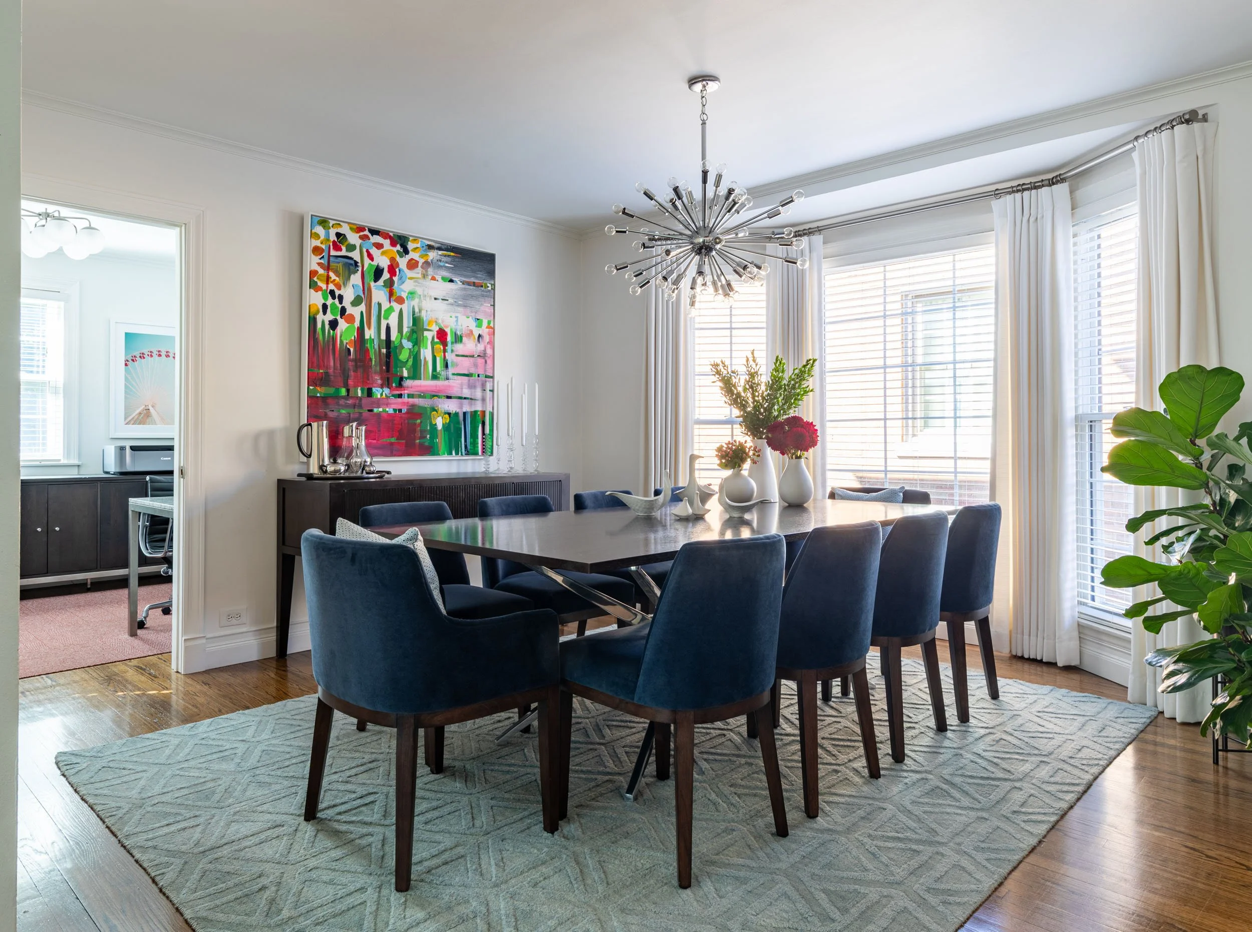 Open concept dining room in Edgebrook, Chicago, IL with modern furnishings, bold abstract artwork, and abundant natural light. Design by Wendy Nobriga Interiors.