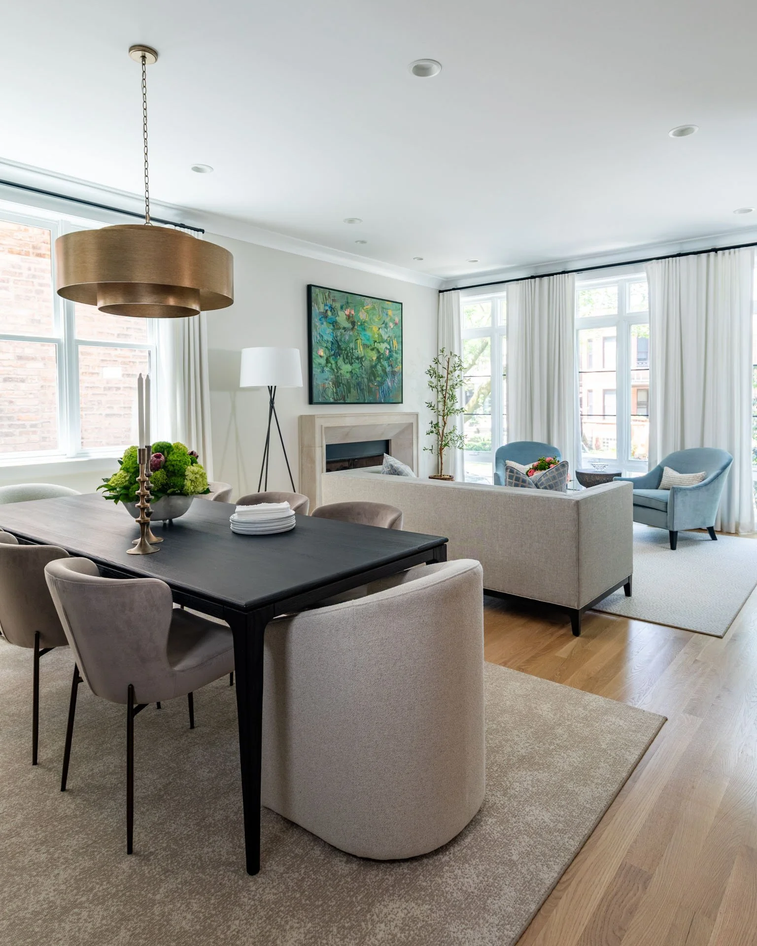 Open concept view of Roscoe Village Chicago dining room and living room, featuring black dining table, neutral seating, and fireplace, designed by Wendy Nobriga Interiors.