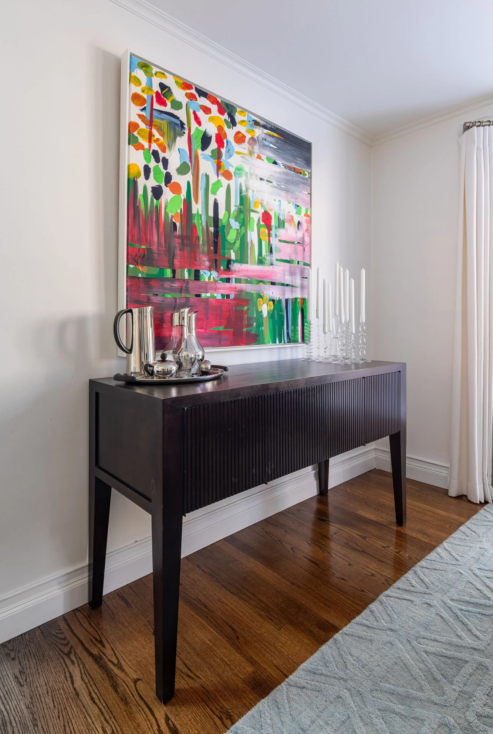 Dining room in Edgebrook, Chicago, IL with a modern sideboard, bold abstract artwork, and curated decorative styling. Design by Wendy Nobriga Interiors.