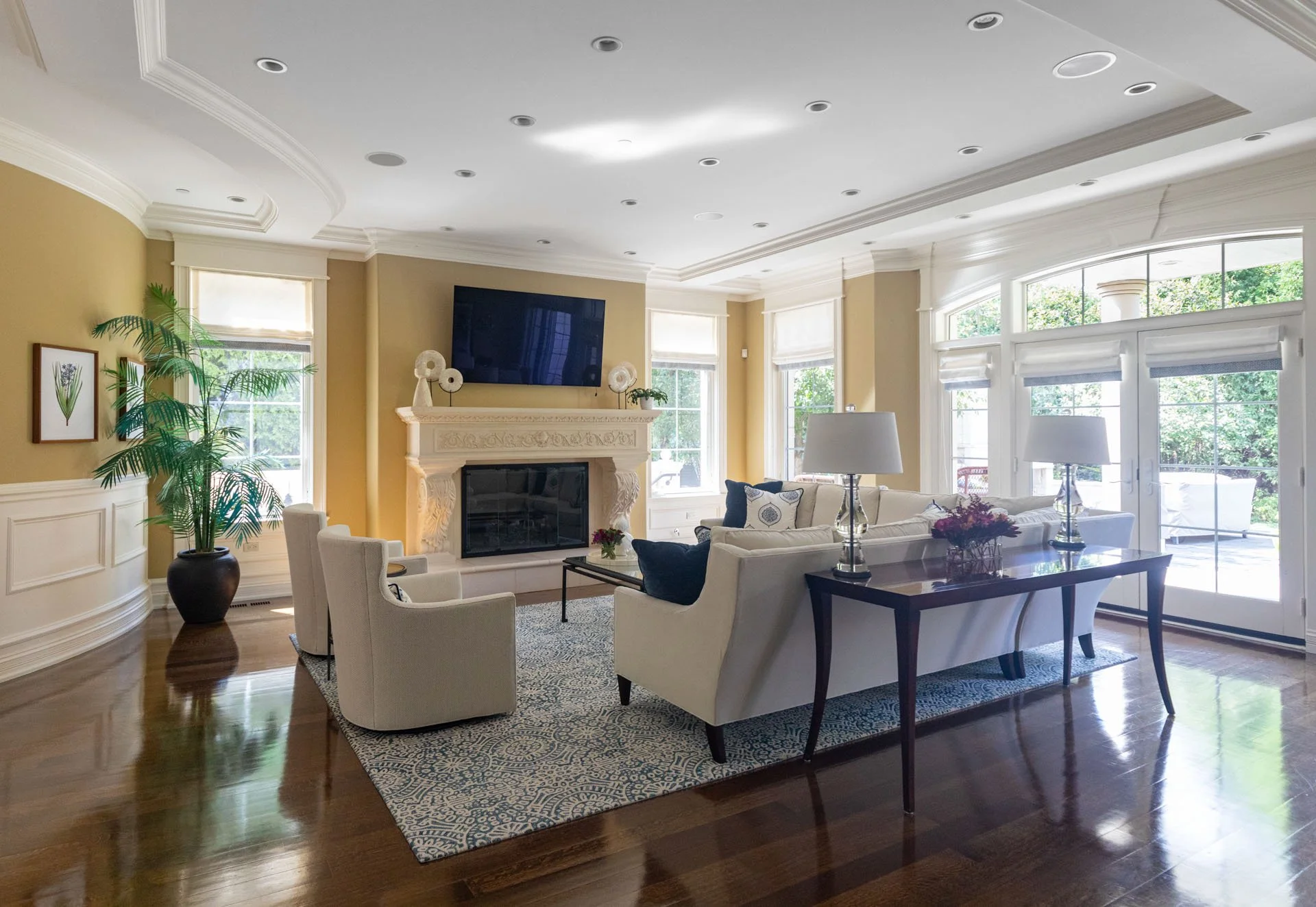 Lincolnwood IL family room with white sofas blue rug marble fireplace and glass doors designed by Wendy Nobriga Interiors