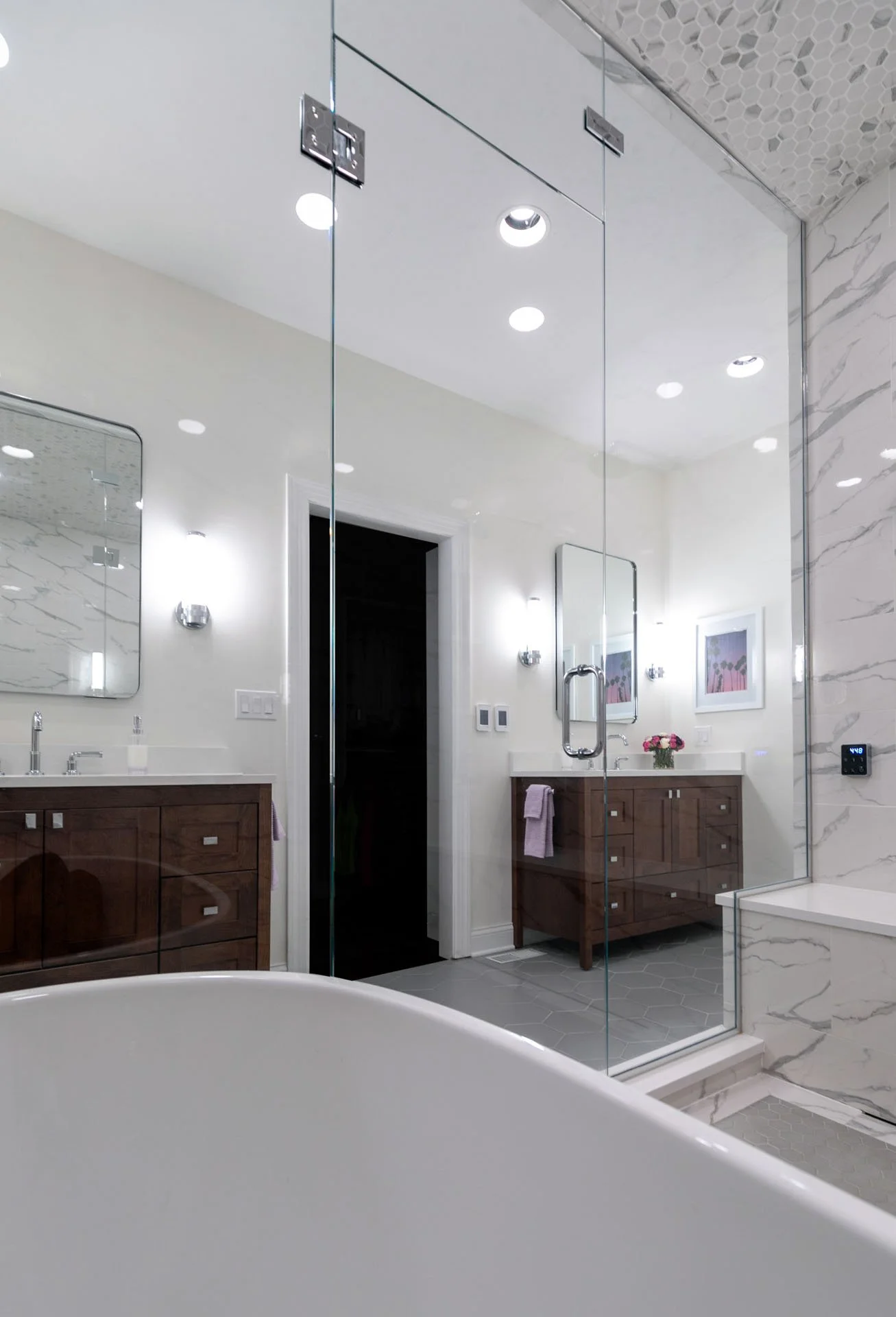 Lake View Chicago primary bathroom with double vanity, wood cabinetry, modern mirrors, and view into wet room with soaking tub and porcelain marble-look tile, designed by Wendy Nobriga Interiors