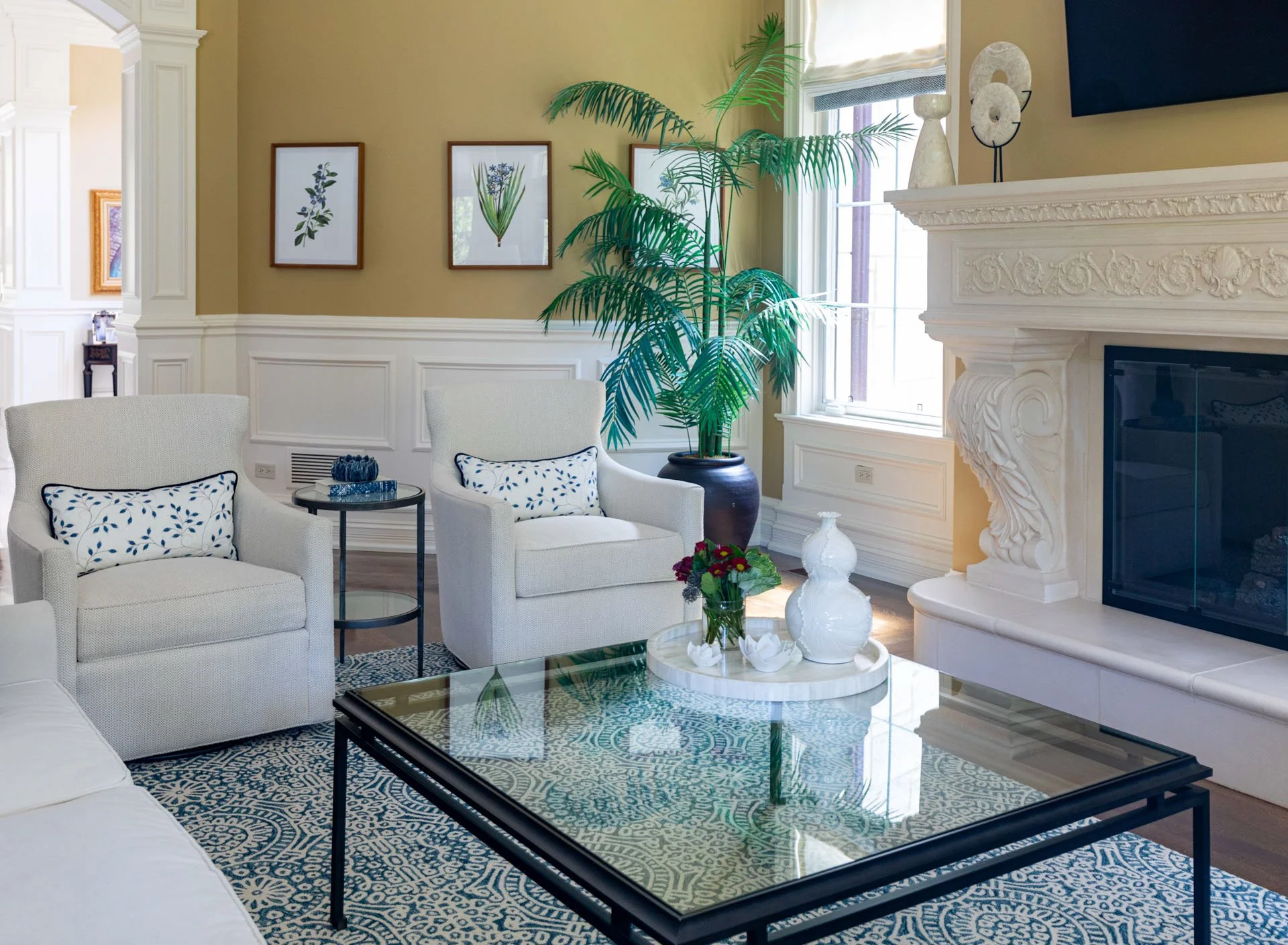 Lincolnwood IL family room seating area with white armchairs glass coffee table and potted palm designed by Wendy Nobriga Interiors