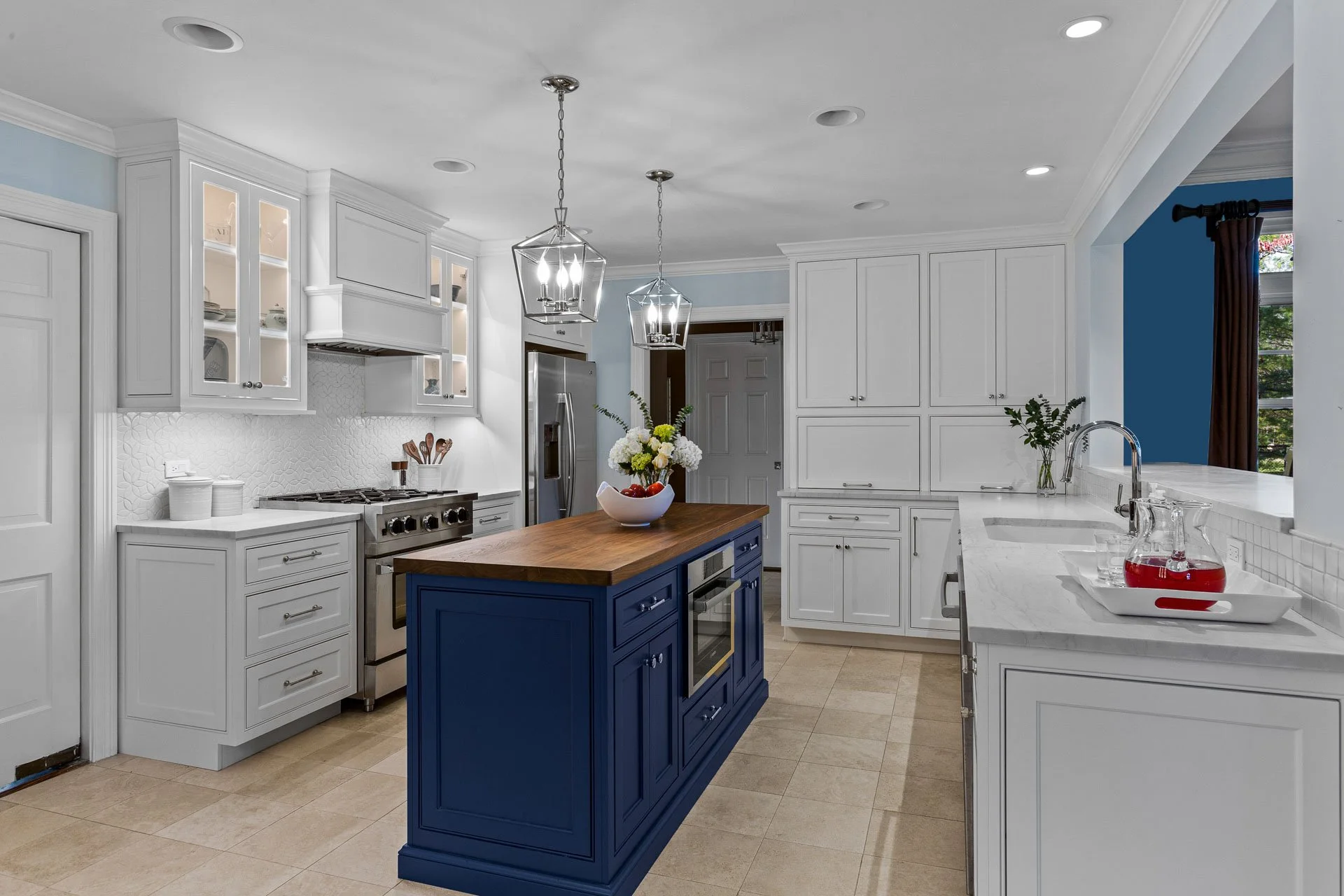 Lake Forest kitchen with navy island, white perimeter cabinets, pendant lighting, and wood countertop, designed by Wendy Nobriga Interiors