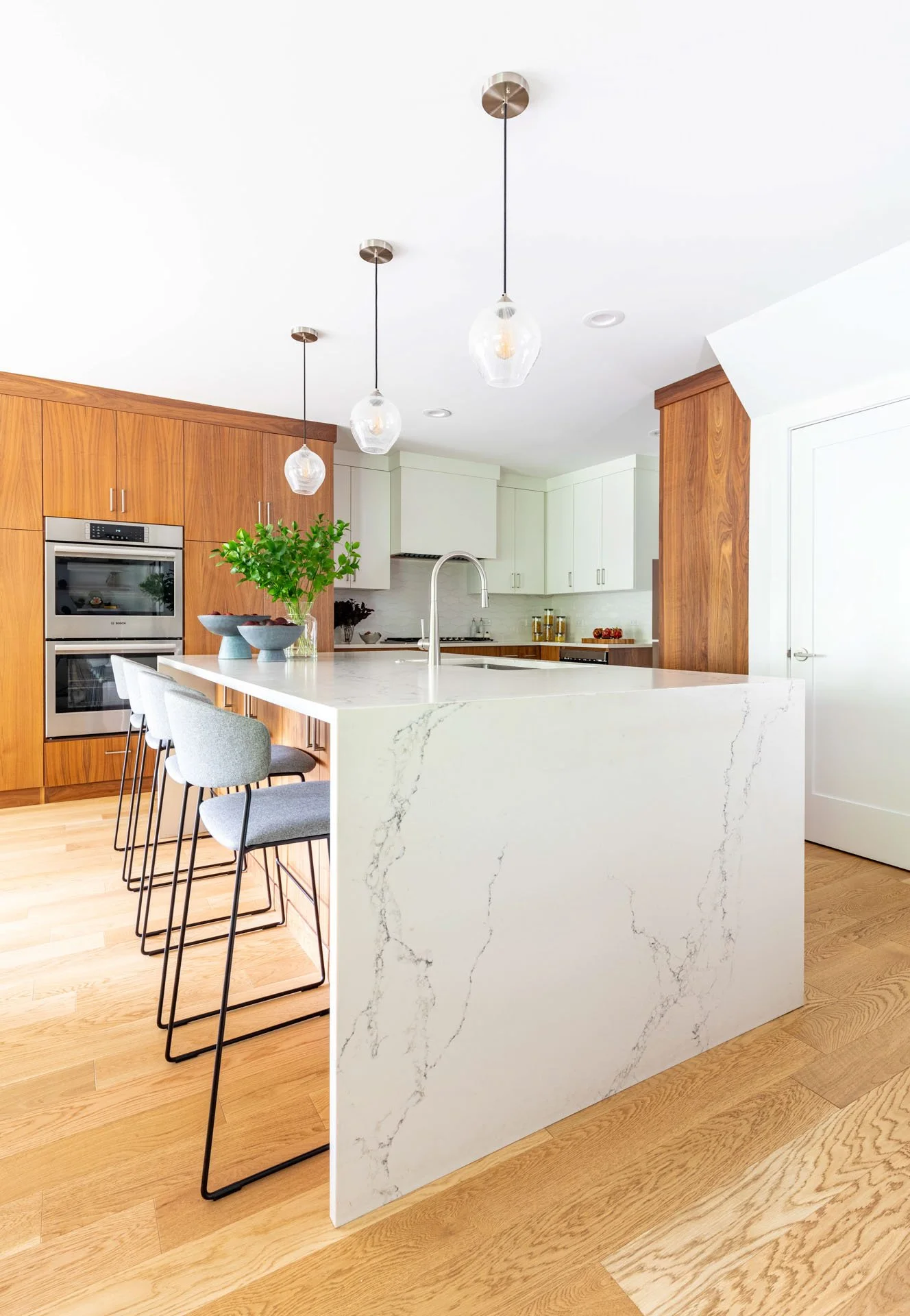 Wildwood Chicago IL modern kitchen with quartz waterfall island, pendant lights, and walnut wood cabinetry, designed by Wendy Nobriga Interiors.