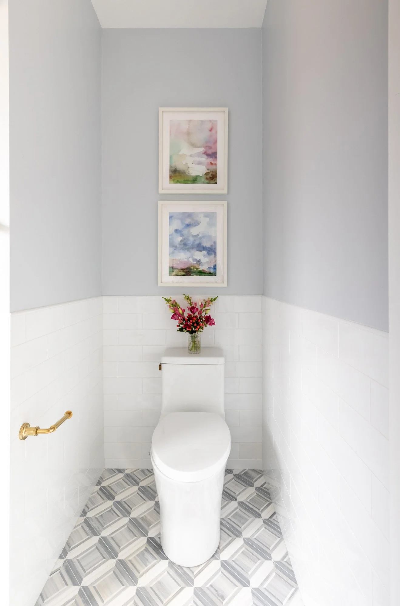 Toilet alcove in a North Edgebrook Chicago primary bathroom featuring marble mosaic flooring, brass accessories, and curated artwork, designed by Wendy Nobriga Interiors.